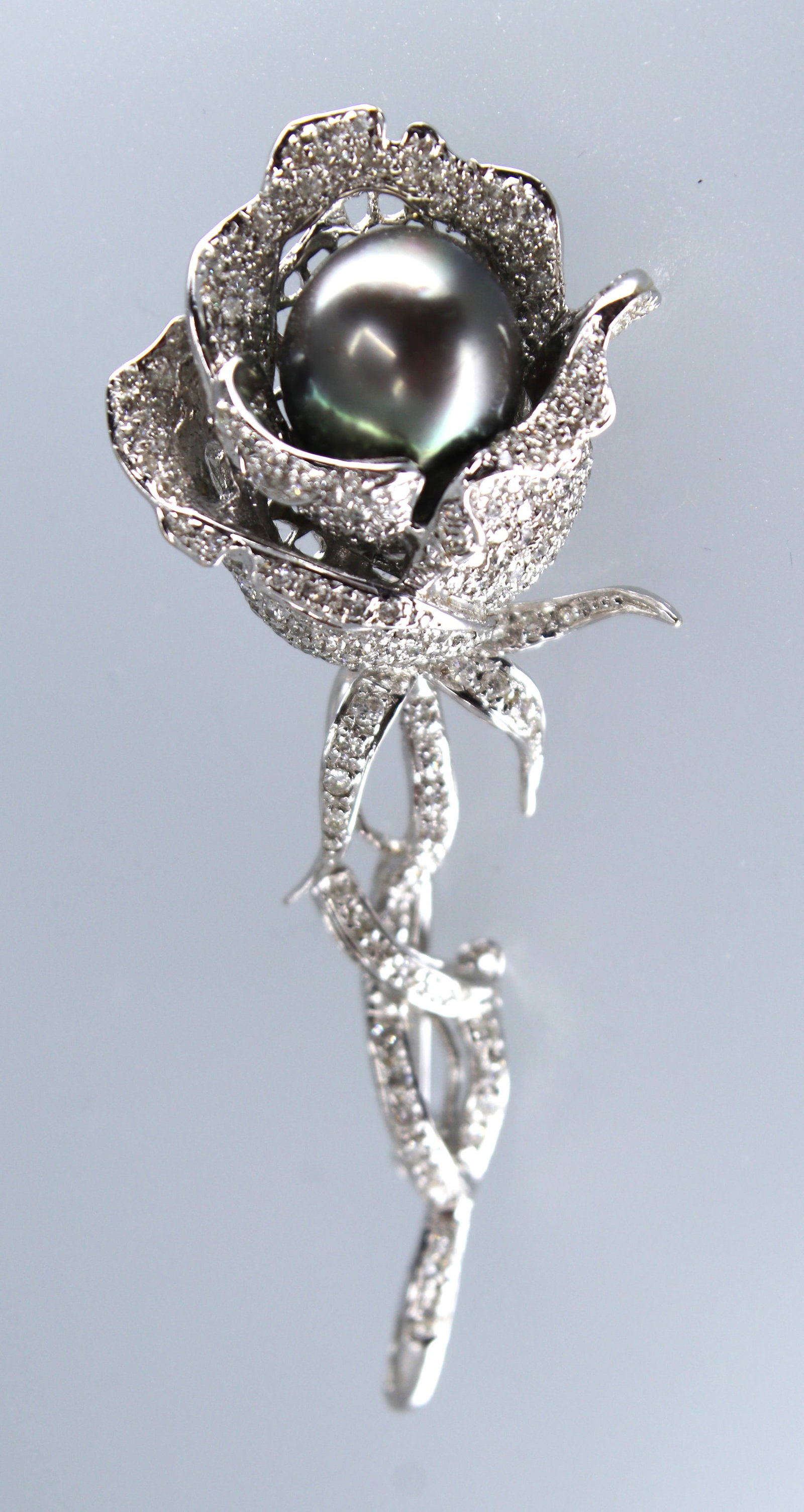 18K WHITE GOLD BLACK PEARL BROOCH WITH DIAMONDS: Title: 18K White Gold Black Pearl Brooch with Diamonds Description: White gold brooch featuring a black pearl and diamond accents. Material: 18K white gold Gemstone Details: Black pearl, diamonds