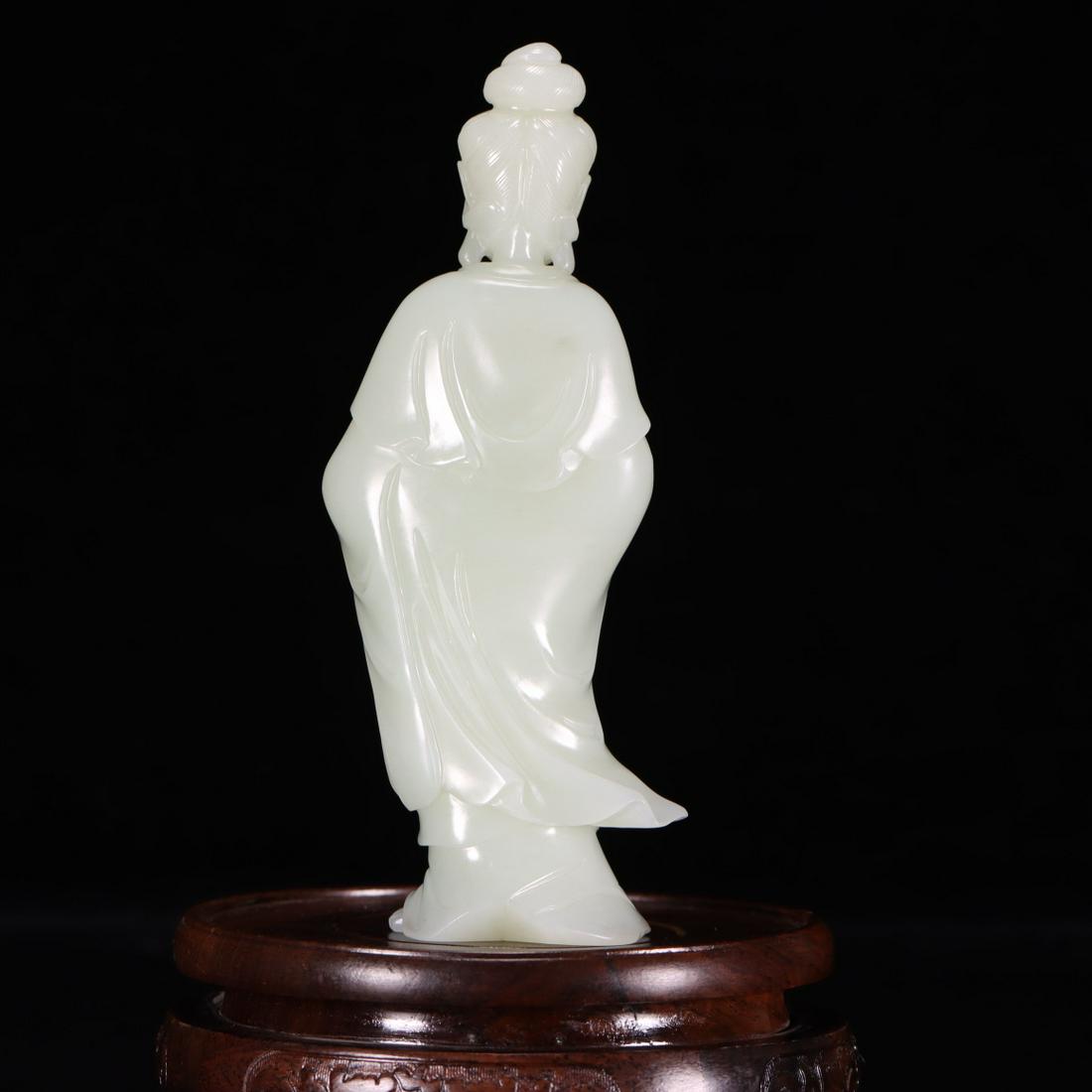 A Hetian Jade Figure Of Guanyin: A Hetian Jade Figure Of Guanyin. Marvelously carved with a figure with a peaceful facial expression rendered clad in long robes, the voluminous drapery elegantly cascading in folds, hair tied into a h
