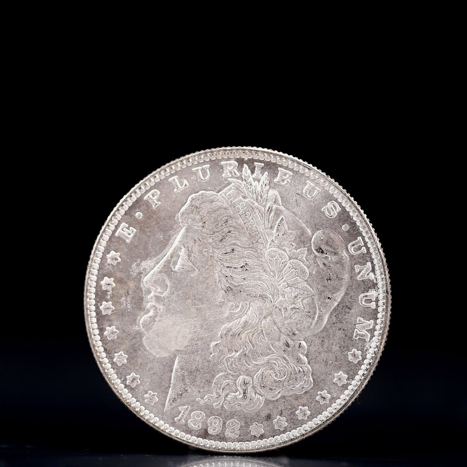 USA Morgan Dollar 1892 Coin: Obv: profile bust with date below and E PLURIBUS UNUM legend and stars around. Rev: eagle with In God we trust above within wreath with UNITED STATES OF AMERICA ONE DOLLAR legend. IN GOD WE TRUST / LI