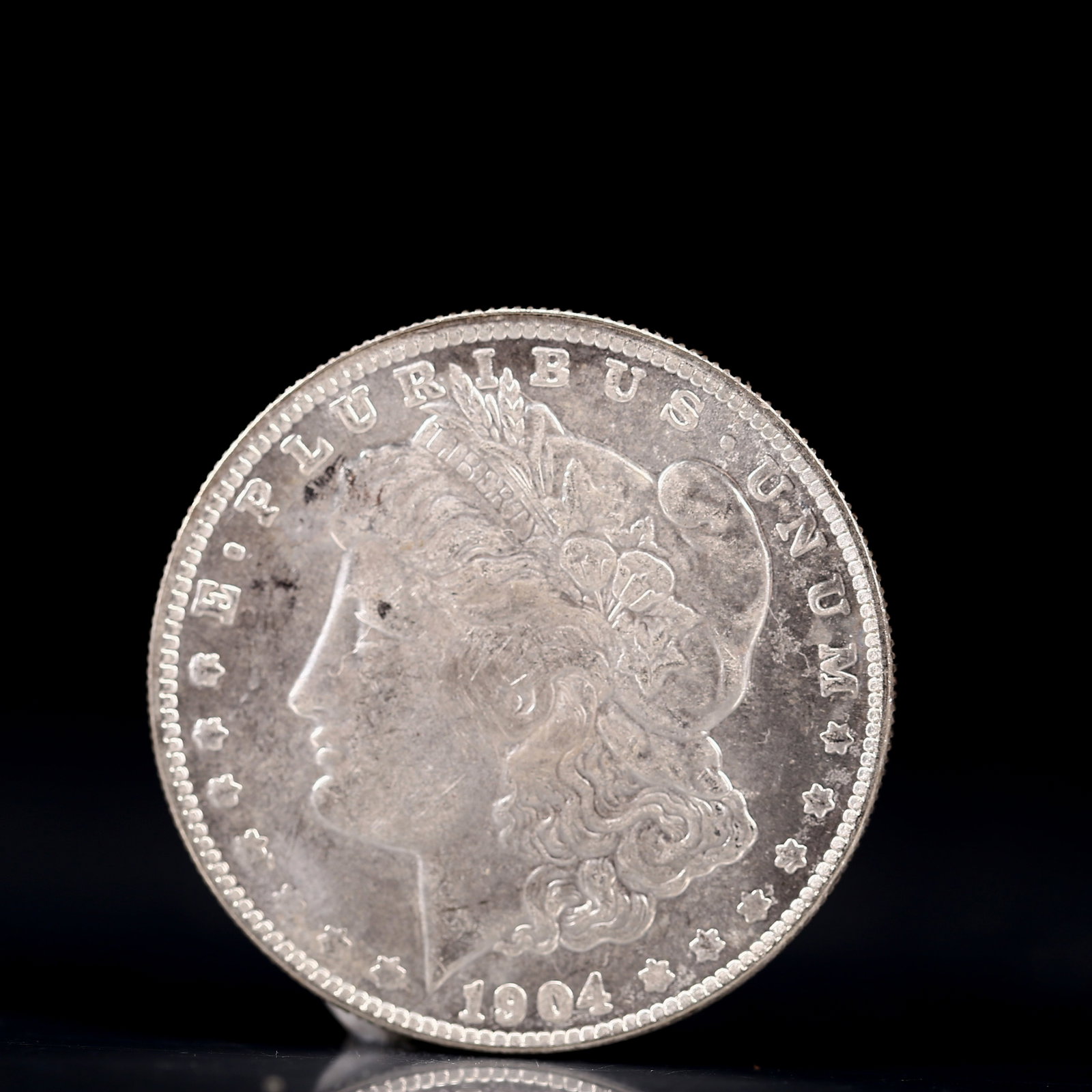 USA Morgan Dollar 1904 Coin: Obv: profile bust with date below and E PLURIBUS UNUM legend and stars around. Rev: eagle with In God we trust above within wreath with UNITED STATES OF AMERICA ONE DOLLAR legend. IN GOD WE TRUST / LI