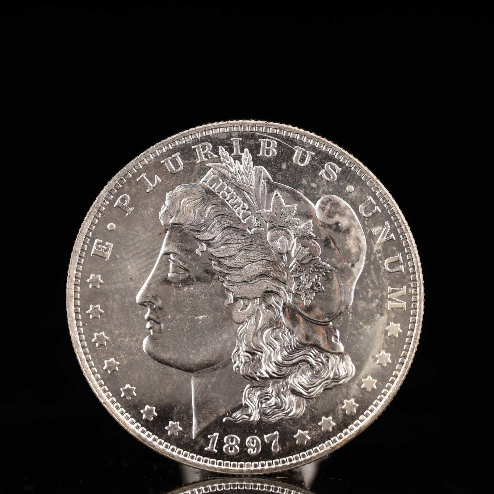 USA Morgan Dollar 1897 Coin: Obv: profile bust with date below and E PLURIBUS UNUM legend and stars around. Rev: eagle with In God we trust above within wreath with UNITED STATES OF AMERICA ONE DOLLAR legend. IN GOD WE TRUST / LI