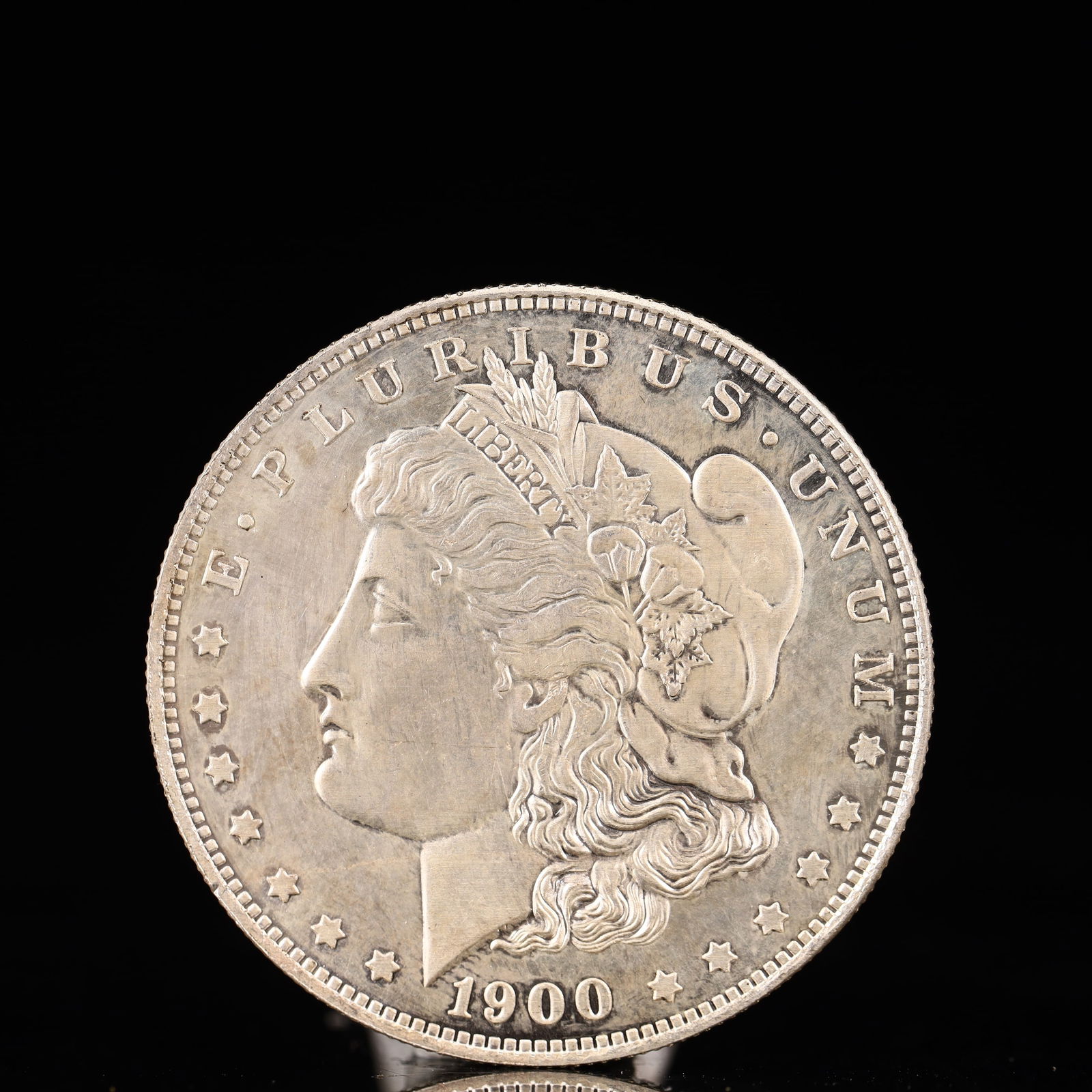 USA Morgan Dollar 1900 Coin: Obv: profile bust with date below and E PLURIBUS UNUM legend and stars around. Rev: eagle with In God we trust above within wreath with UNITED STATES OF AMERICA ONE DOLLAR legend. IN GOD WE TRUST / LI