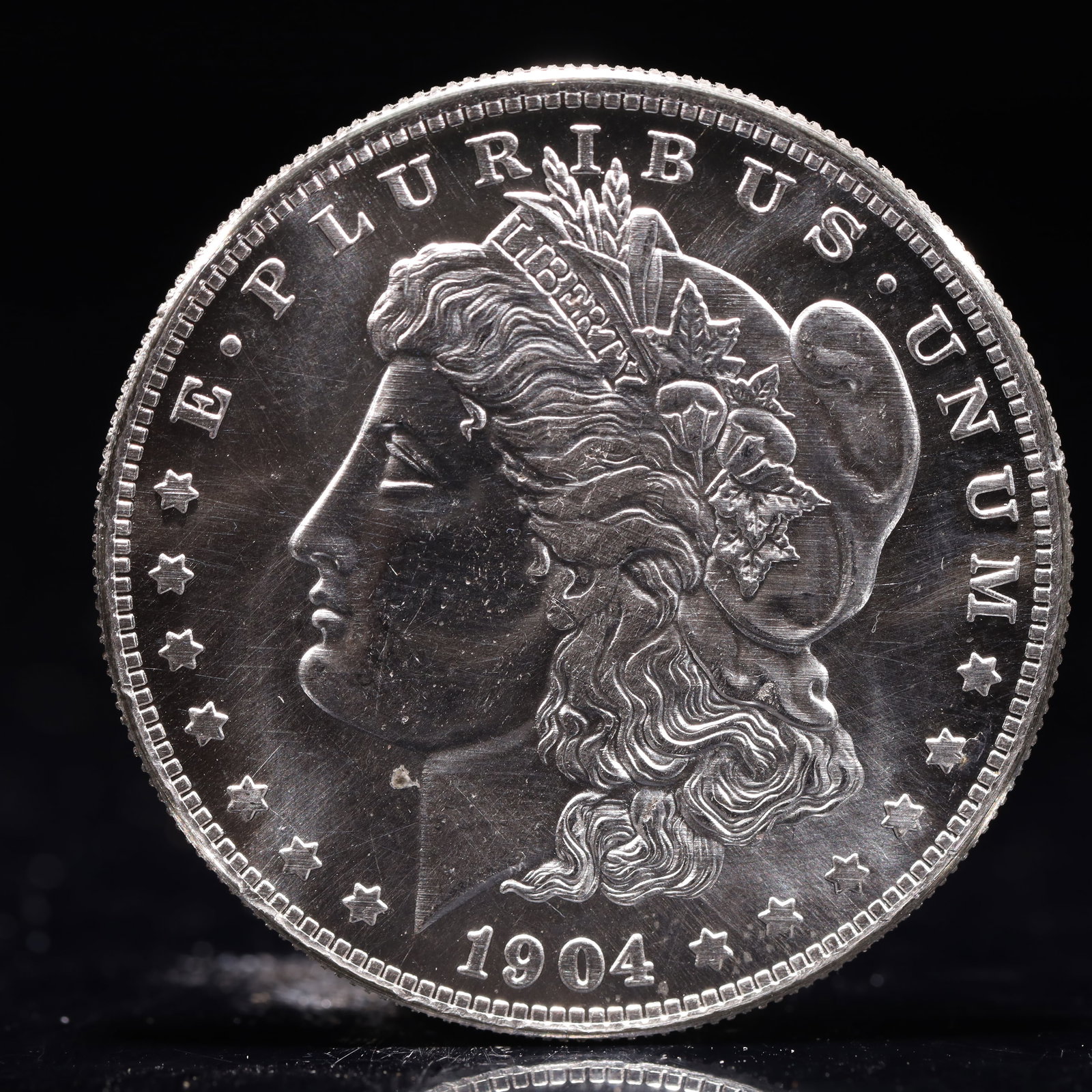 USA Morgan Dollar 1904 Coin: Obv: profile bust with date below and E PLURIBUS UNUM legend and stars around. Rev: eagle with In God we trust above within wreath with UNITED STATES OF AMERICA ONE DOLLAR legend. IN GOD WE TRUST / LI