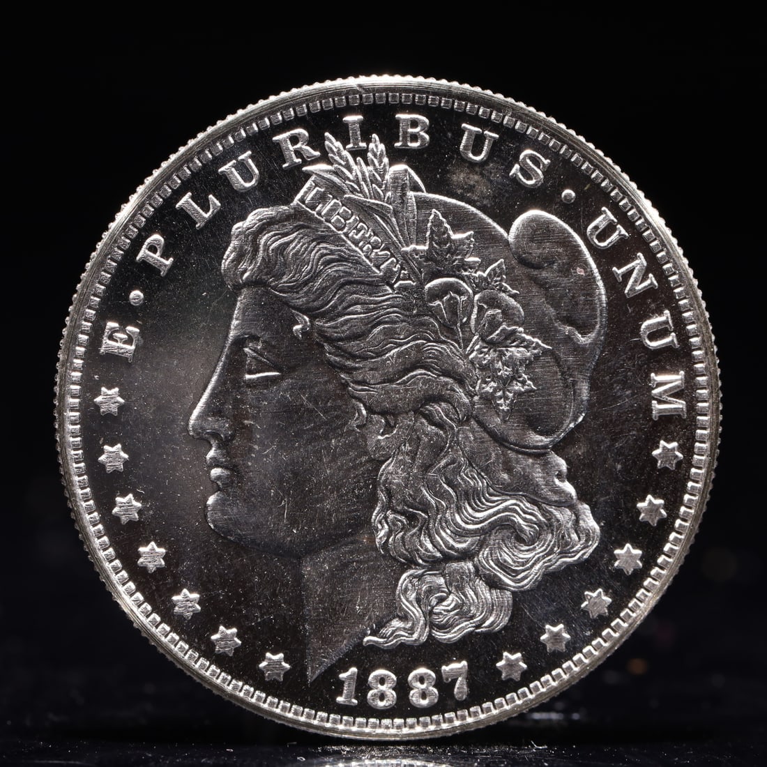 USA Morgan Dollar 1887 Coin: Obv: profile bust with date below and E PLURIBUS UNUM legend and stars around. Rev: eagle with In God we trust above within wreath with UNITED STATES OF AMERICA ONE DOLLAR legend. IN GOD WE TRUST / LI