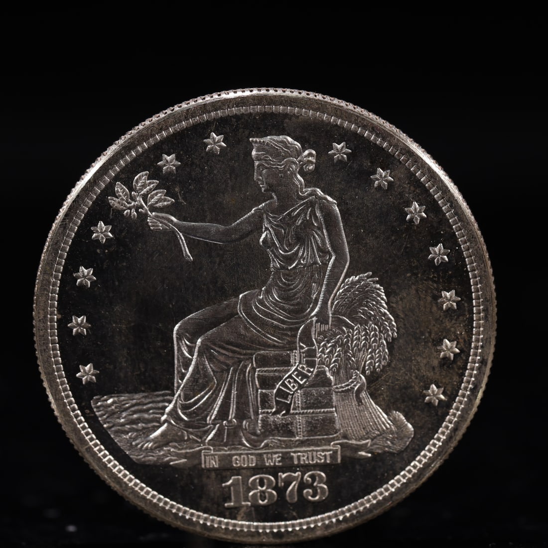 USA Trade Dollar 1873 Coin: American coin. Obverse: Liberty seated on a pedestal facing the sea to the left holding olive branches surrounded by 13 stars. IN GOD WE TRUST / LIBERTY / 1873. Reverse: An eagle holding branches with