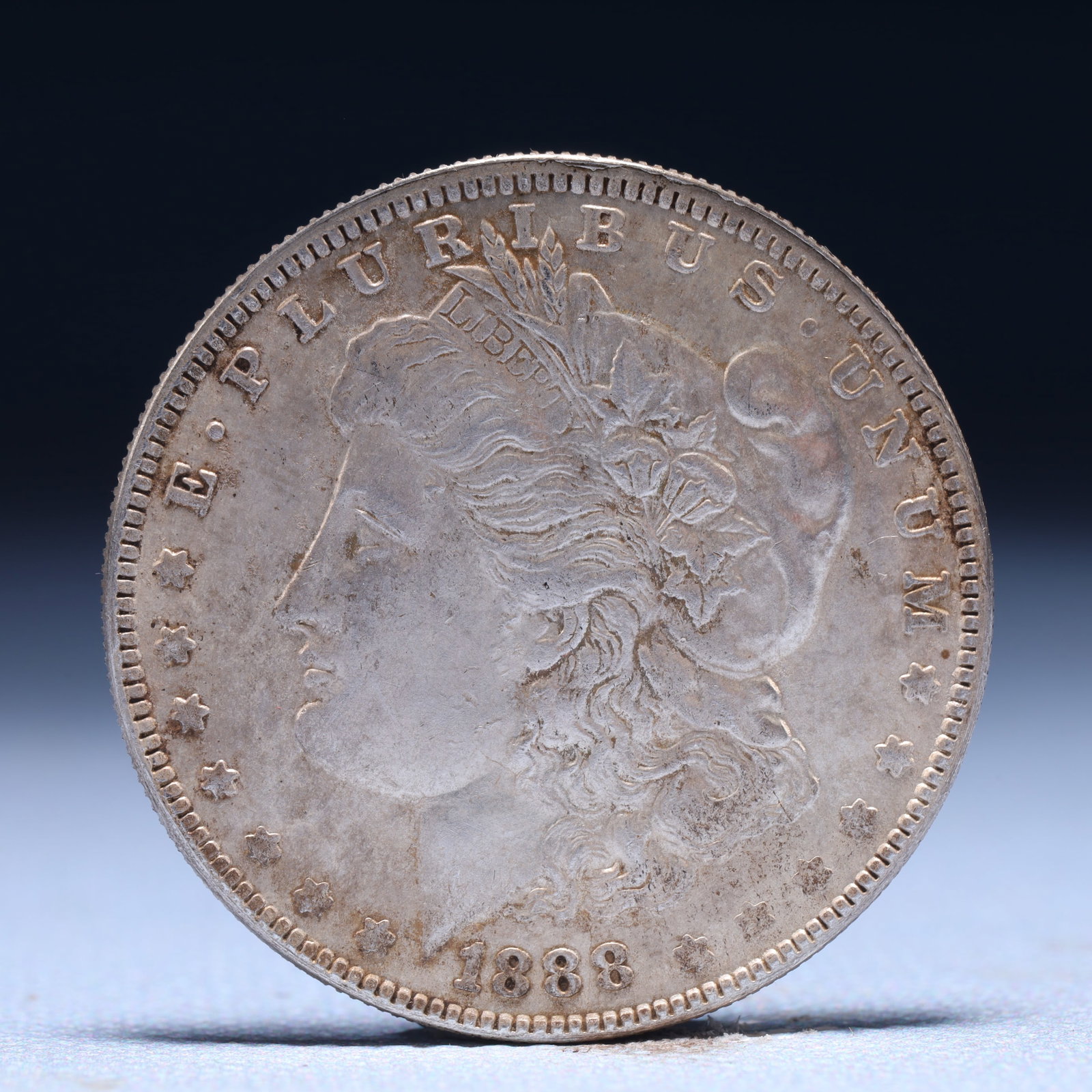 USA Morgan Dollar 1888 Coin: Obv: profile bust with date below and E PLURIBUS UNUM legend and stars around. Rev: eagle with In God we trust above within wreath with UNITED STATES OF AMERICA ONE DOLLAR legend. IN GOD WE TRUST / LI