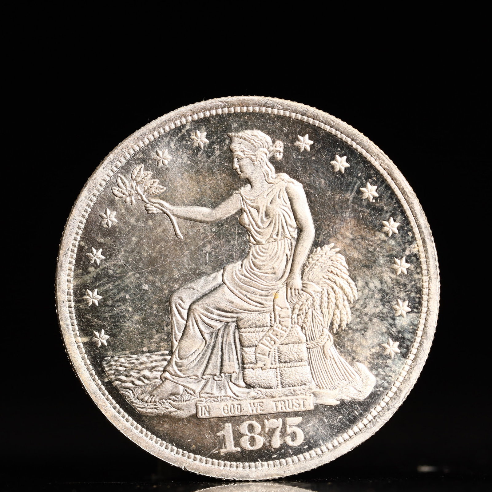 USA Trade Dollar 1875 Coin: American coin. Obverse: Liberty seated on a pedestal facing the sea to the left holding olive branches surrounded by 13 stars. IN GOD WE TRUST / LIBERTY / 1875. Reverse: An eagle holding branches with