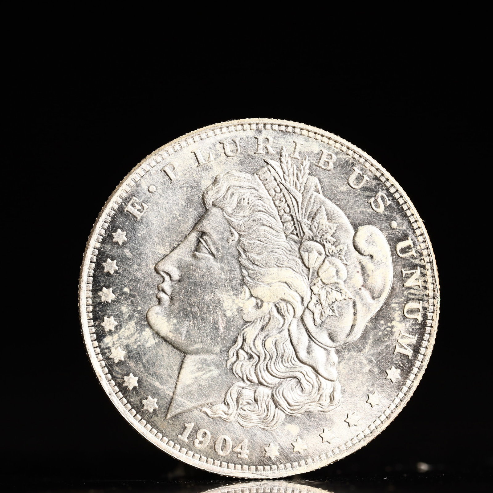 USA Morgan Dollar 1904 Coin: Obv: profile bust with date below and E PLURIBUS UNUM legend and stars around. Rev: eagle with In God we trust above within wreath with UNITED STATES OF AMERICA ONE DOLLAR legend. IN GOD WE TRUST /