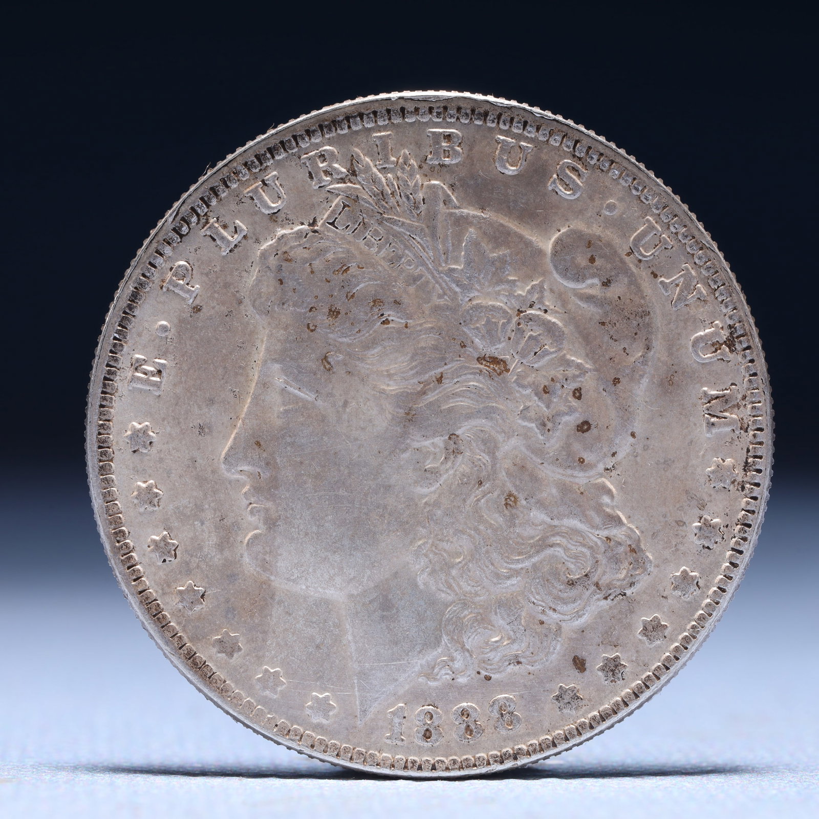 USA Morgan Dollar 1888 Coin: Obv: profile bust with date below and E PLURIBUS UNUM legend and stars around. Rev: eagle with In God we trust above within wreath with UNITED STATES OF AMERICA ONE DOLLAR legend. IN GOD WE TRUST / LI
