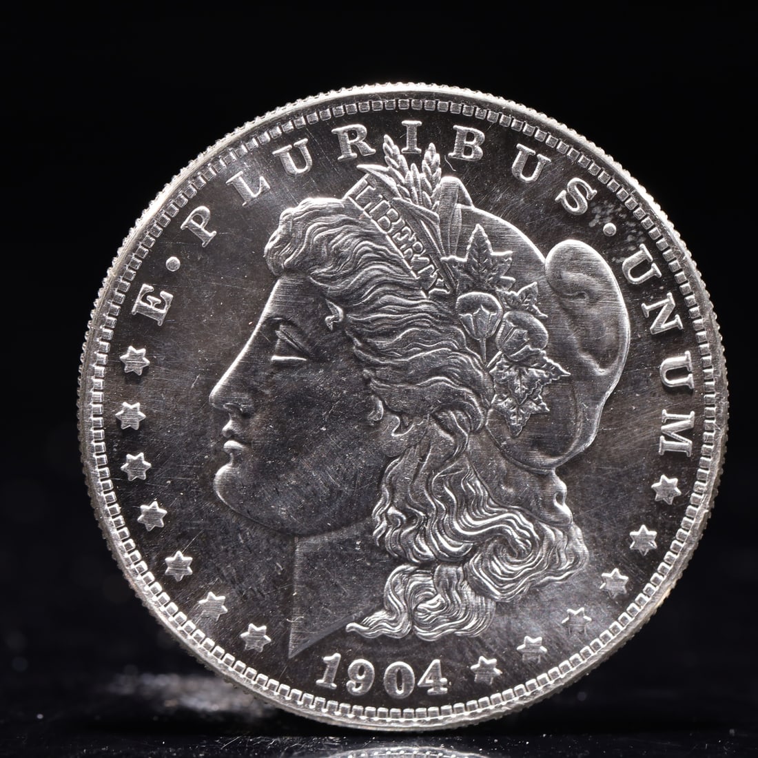 USA Morgan Dollar 1904 Coin: Obv: profile bust with date below and E PLURIBUS UNUM legend and stars around. Rev: eagle with In God we trust above within wreath with UNITED STATES OF AMERICA ONE DOLLAR legend. IN GOD WE TRUST /