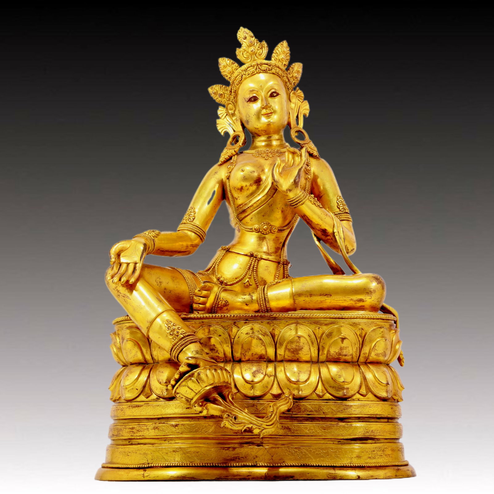 A solemn gilt bronze statue of green Tara: A solemn gilt-bronze green Tara statue, Qianlong seven-character inscription, Qing Dynasty, China. Tara has an elegant posture with a peaceful and compassionate expression. Her face is soft and solemn