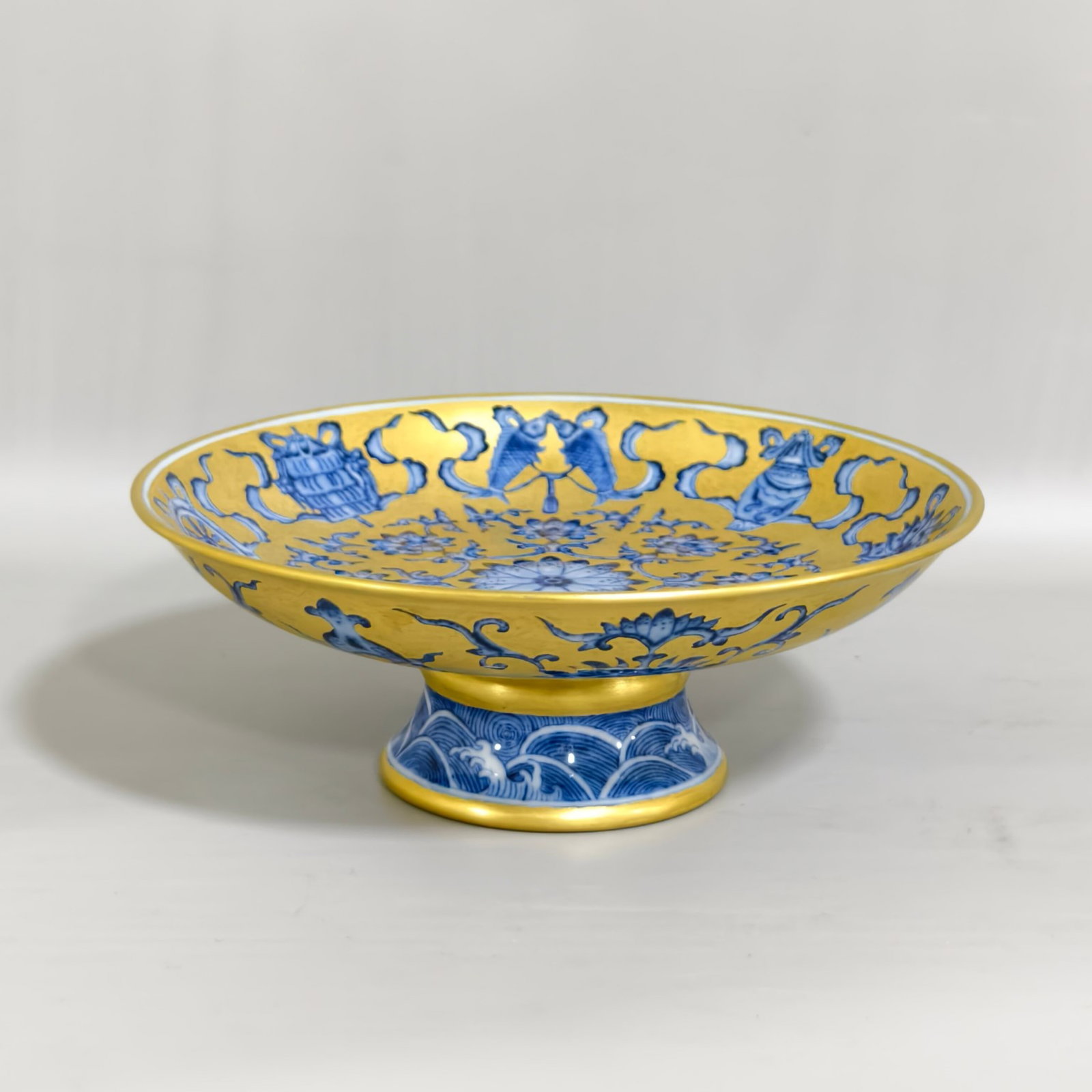 An Exquisite Gold Ground Blue and White Eight Treasures Pattern Stem Plate: An Exquisite Gold Ground Blue and White Eight Treasures Pattern Stem Plate,Qing Dynasty,China,Qianlong Six-character Mark,Size:2.3inx6.1in 金地青花八宝纹ƌ