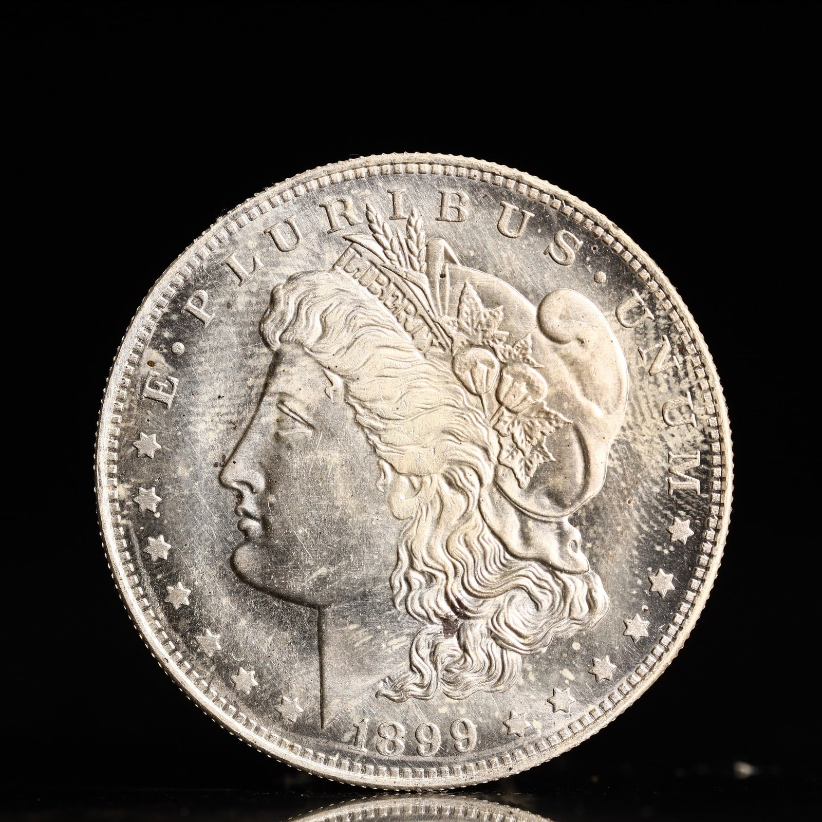 USA Morgan Dollar 1899 Coin: Obv: profile bust with date below and E PLURIBUS UNUM legend and stars around. Rev: eagle with In God we trust above within wreath with UNITED STATES OF AMERICA ONE DOLLAR legend. IN GOD WE TRUST / LI