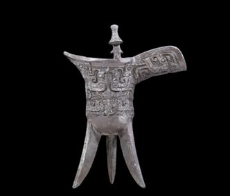 A precious bronze tripod cup with animal masks