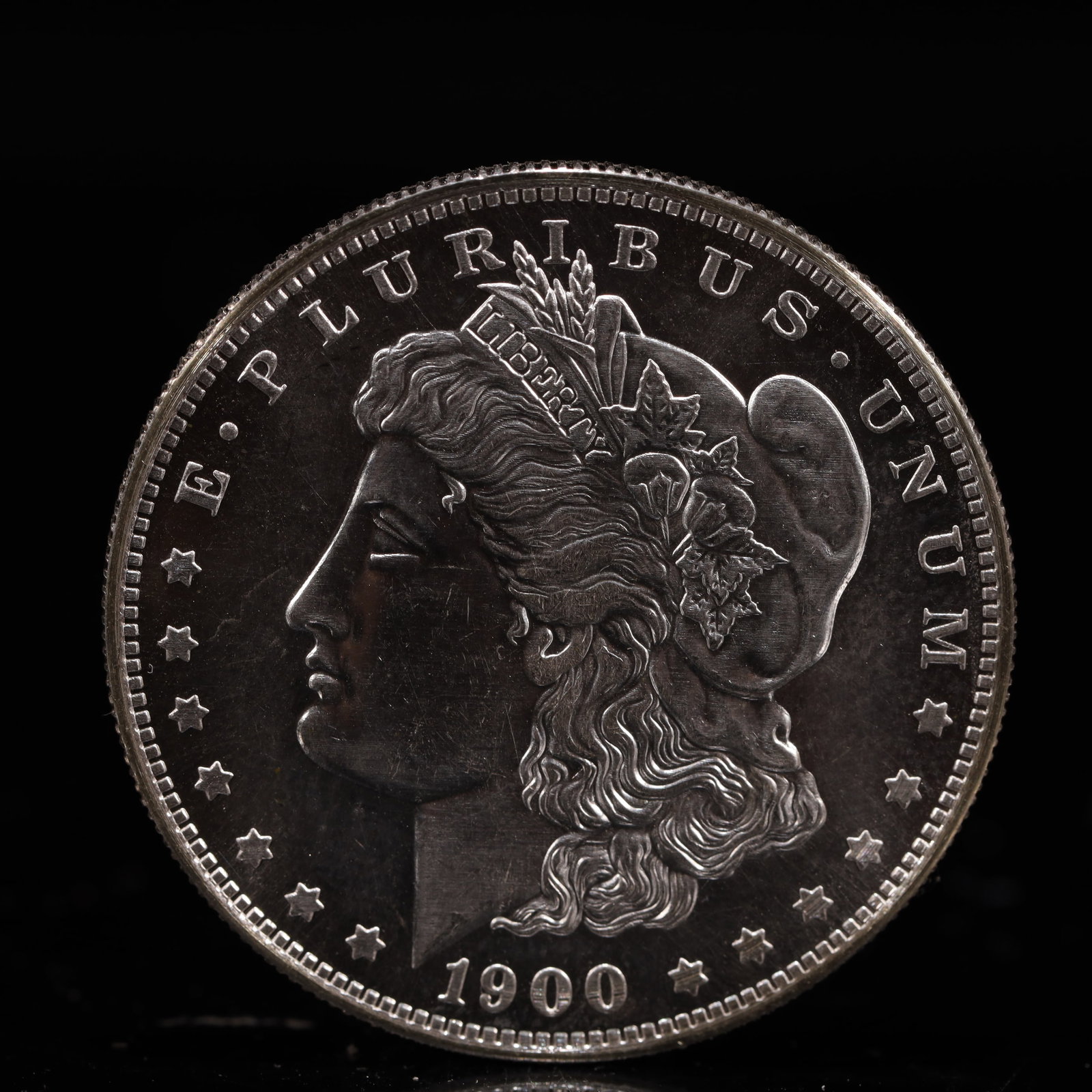 USA Morgan Dollar 1900 Coin: Obv: profile bust with date below and E PLURIBUS UNUM legend and stars around. Rev: eagle with In God we trust above within wreath with UNITED STATES OF AMERICA ONE DOLLAR legend. IN GOD WE TRUST / LI