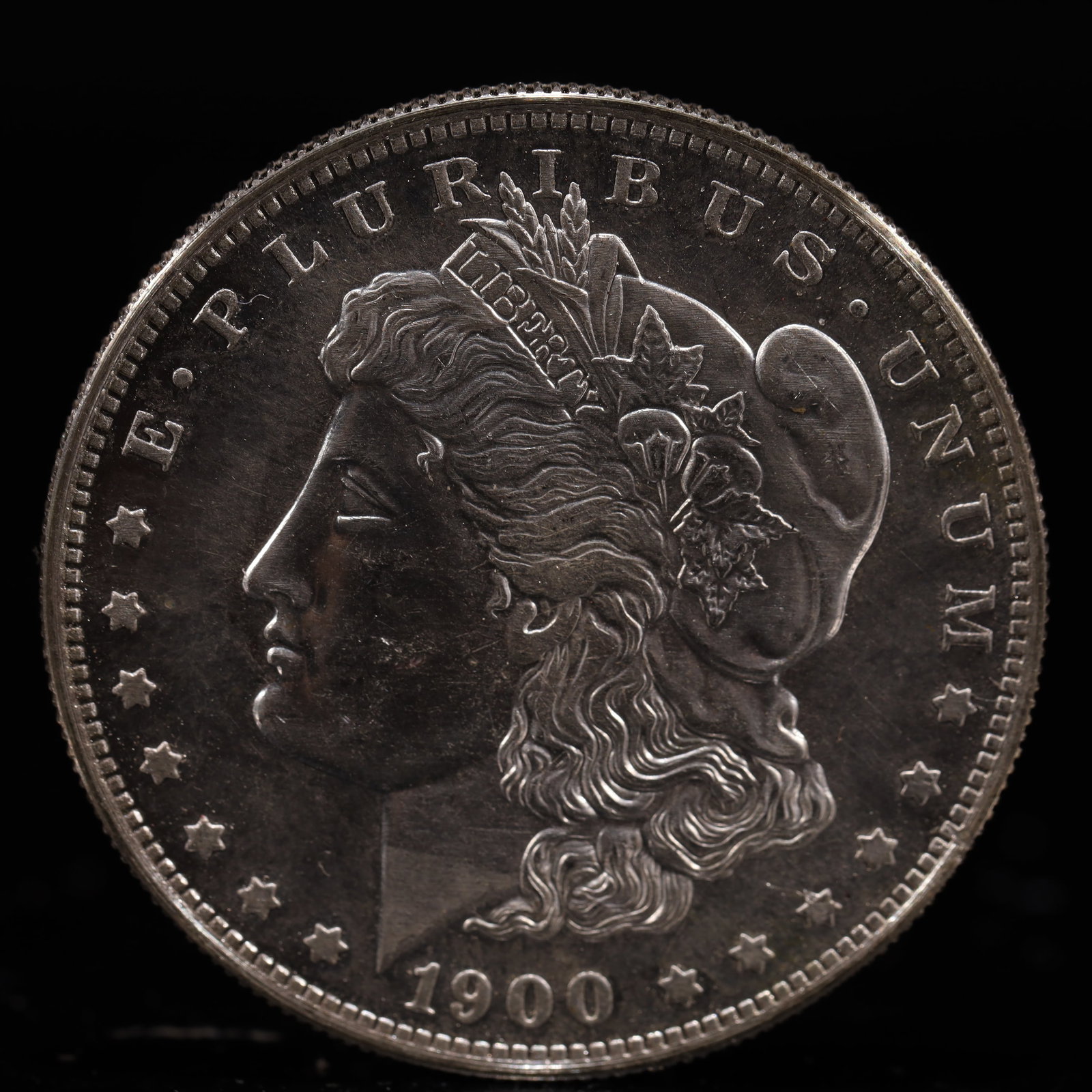 USA Morgan Dollar 1900 Coin: Obv: profile bust with date below and E PLURIBUS UNUM legend and stars around. Rev: eagle with In God we trust above within wreath with UNITED STATES OF AMERICA ONE DOLLAR legend. IN GOD WE TRUST / LI