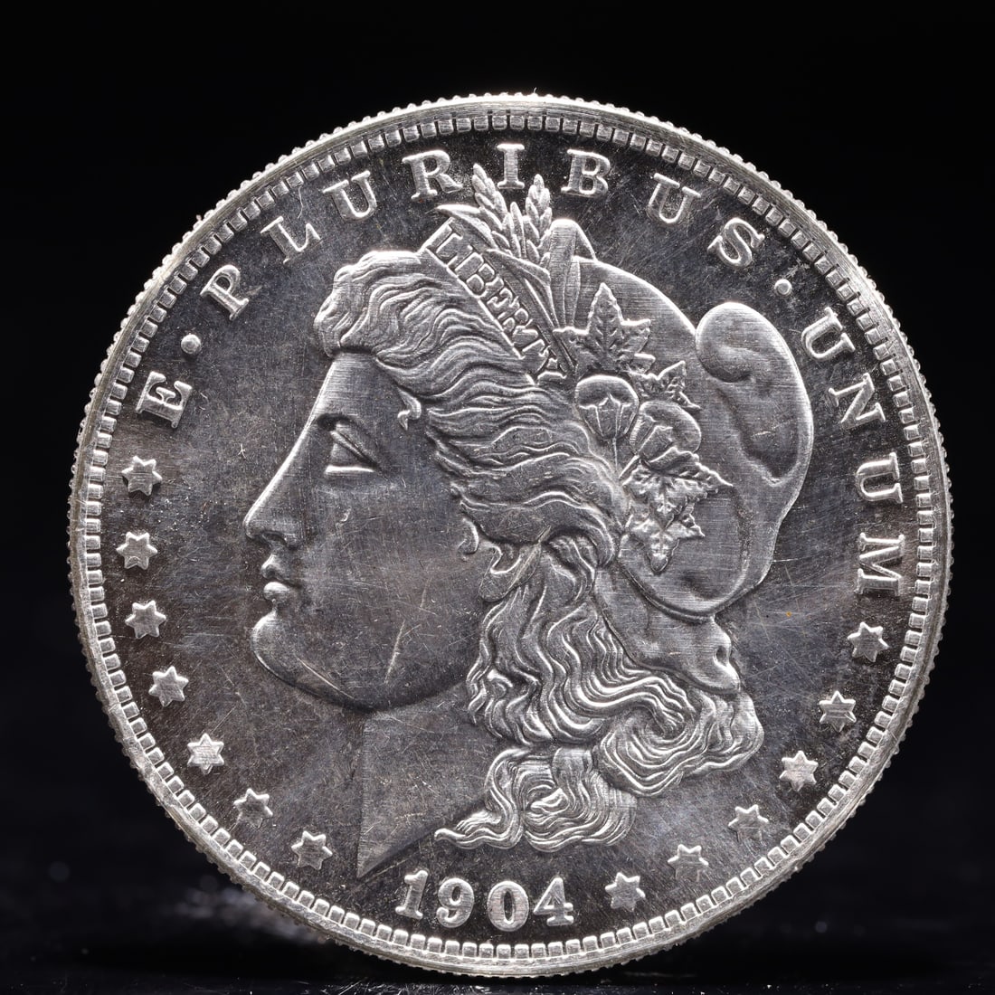 USA Morgan Dollar 1904 Coin: Obv: profile bust with date below and E PLURIBUS UNUM legend and stars around. Rev: eagle with In God we trust above within wreath with UNITED STATES OF AMERICA ONE DOLLAR legend. IN GOD WE TRUST / LI