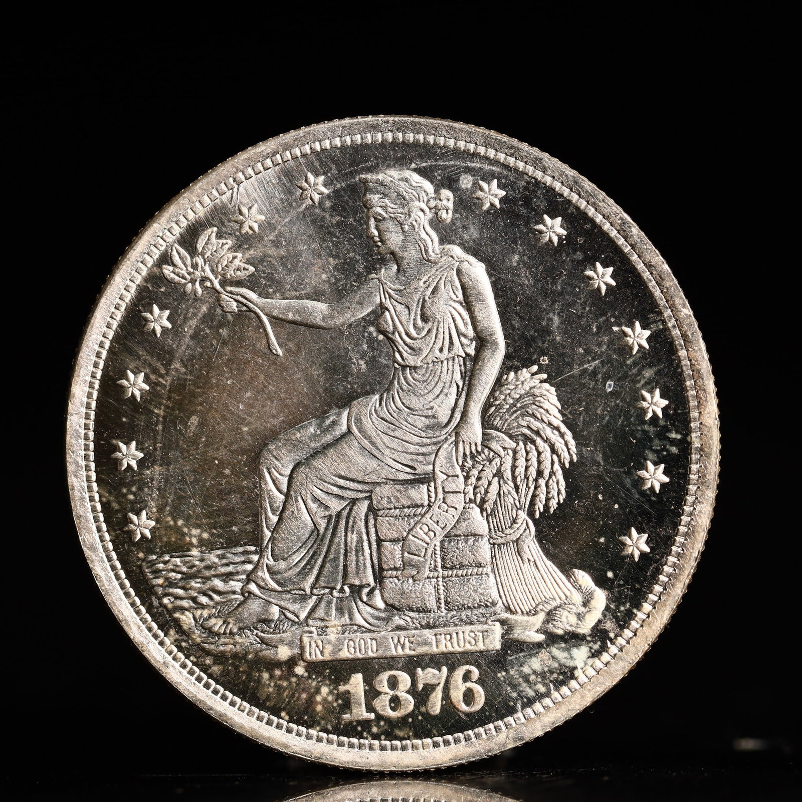 USA Trade Dollar 1876 Coin: American coin. Obverse: Liberty seated on a pedestal facing the sea to the left holding olive branches surrounded by 13 stars. IN GOD WE TRUST / LIBERTY / 1876. Reverse: An eagle holding branches