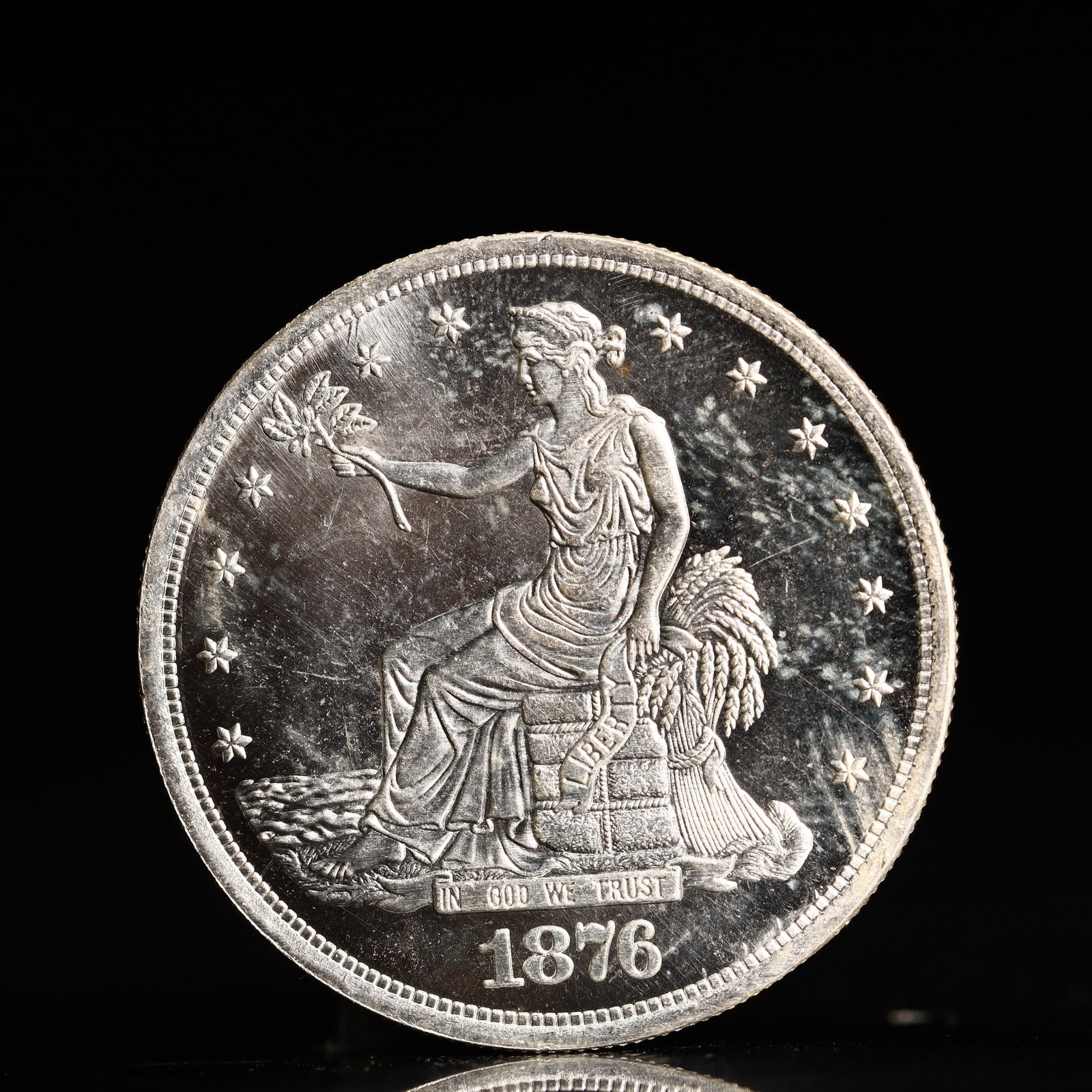 USA Trade Dollar 1876 Coin: American coin. Obverse: Liberty seated on a pedestal facing the sea to the left holding olive branches surrounded by 13 stars. IN GOD WE TRUST / LIBERTY / 1876. Reverse: An eagle holding branches
