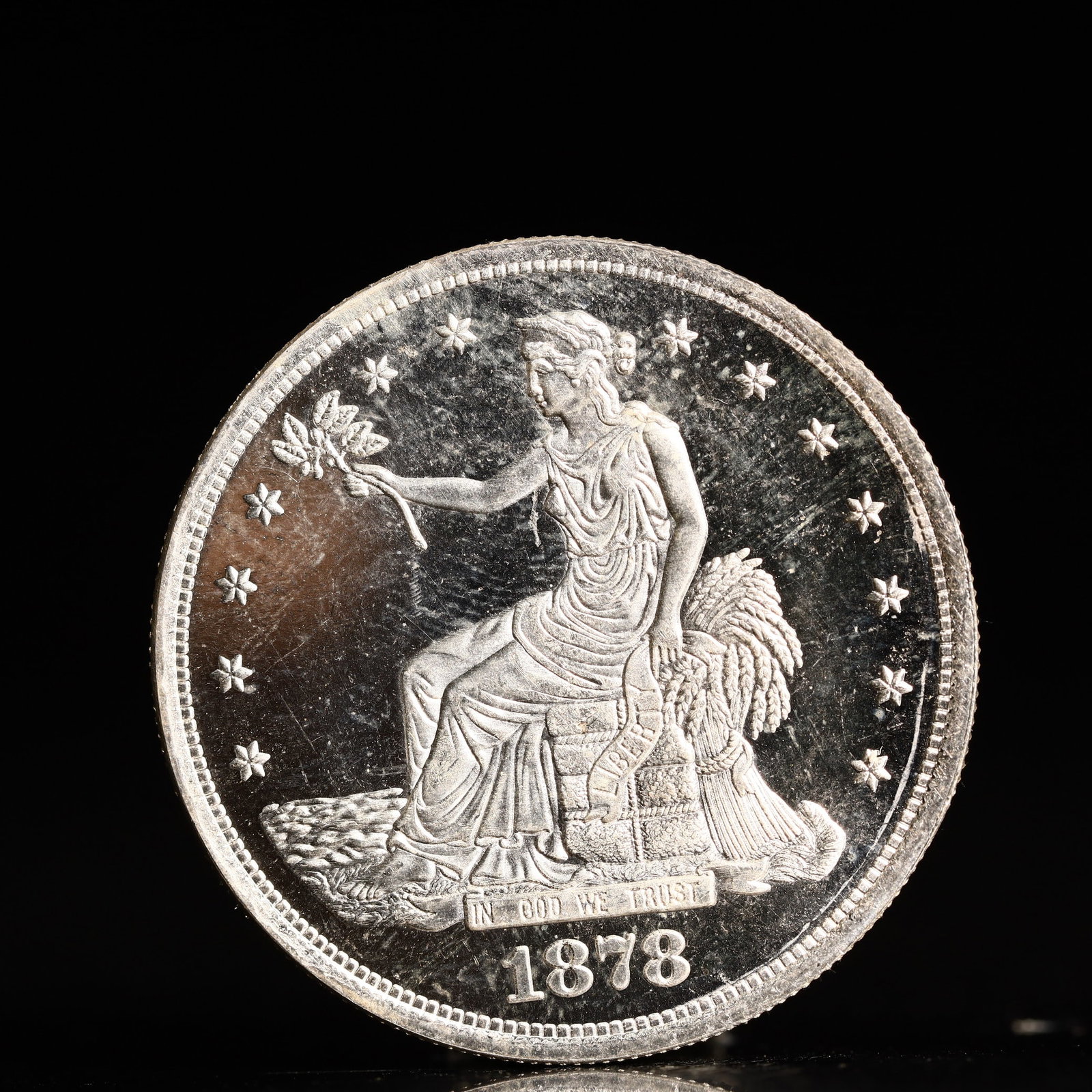 USA Trade Dollar 1878 Coin: American coin. Obverse: Liberty seated on a pedestal facing the sea to the left holding olive branches surrounded by 13 stars. IN GOD WE TRUST / LIBERTY / 1878. Reverse: An eagle holding branches with