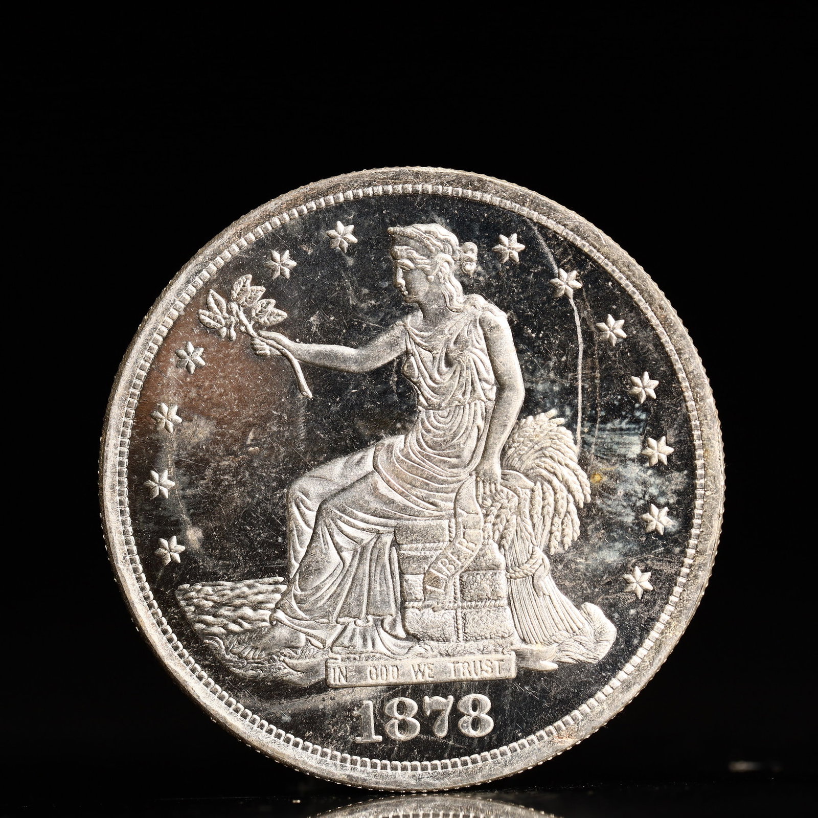 USA Trade Dollar 1878 Coin: American coin. Obverse: Liberty seated on a pedestal facing the sea to the left holding olive branches surrounded by 13 stars. IN GOD WE TRUST / LIBERTY / 1878. Reverse: An eagle holding branches with