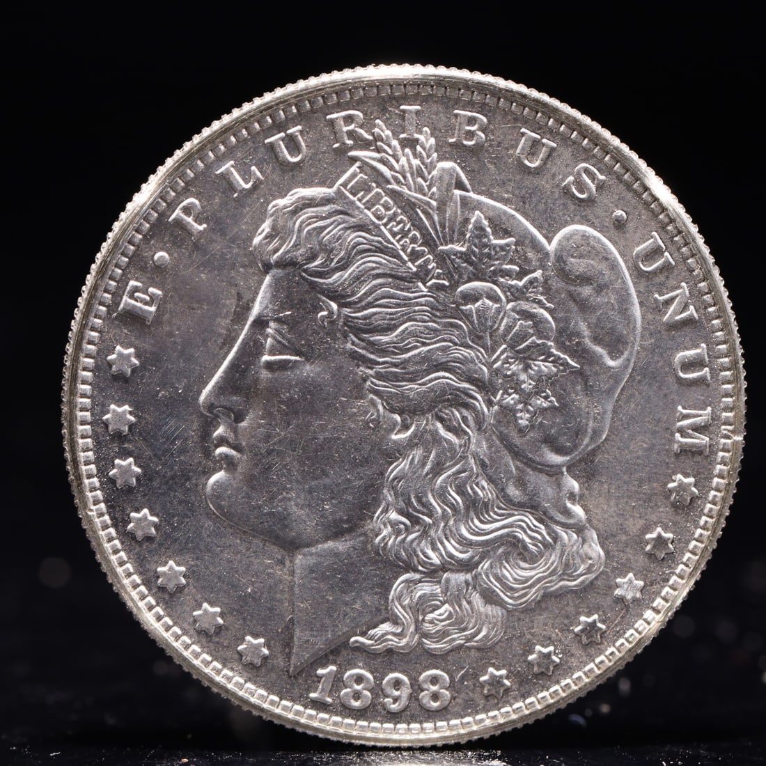 USA Morgan Dollar 1898 Coin: Obv: profile bust with date below and E PLURIBUS UNUM legend and stars around. Rev: eagle with In God we trust above within wreath with UNITED STATES OF AMERICA ONE DOLLAR legend. IN GOD WE TRUST / LI