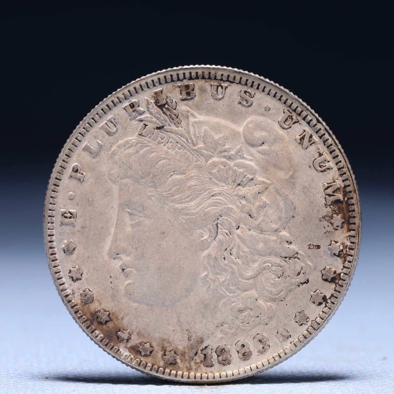 USA Morgan Dollar 1889 Coin: Obv: profile bust with date below and E PLURIBUS UNUM legend and stars around. Rev: eagle with In God we trust above within wreath with UNITED STATES OF AMERICA ONE DOLLAR legend. IN GOD WE TRUST / LI