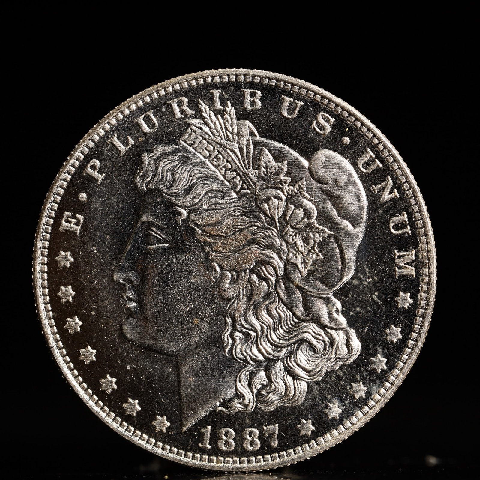 USA Morgan Dollar 1887 Coin: Obv: profile bust with date below and E PLURIBUS UNUM legend and stars around. Rev: eagle with In God we trust above within wreath with UNITED STATES OF AMERICA ONE DOLLAR legend. IN GOD WE TRUST / LI