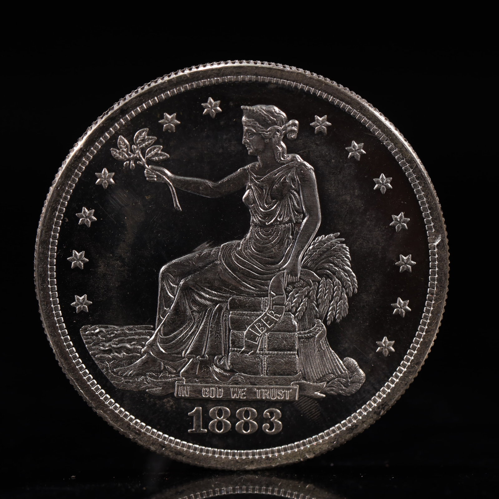USA Trade Dollar 1883 Coin: American coin. Obverse: Liberty seated on a pedestal facing the sea to the left holding olive branches surrounded by 13 stars. IN GOD WE TRUST / LIBERTY / 1883. Reverse: An eagle holding branches with