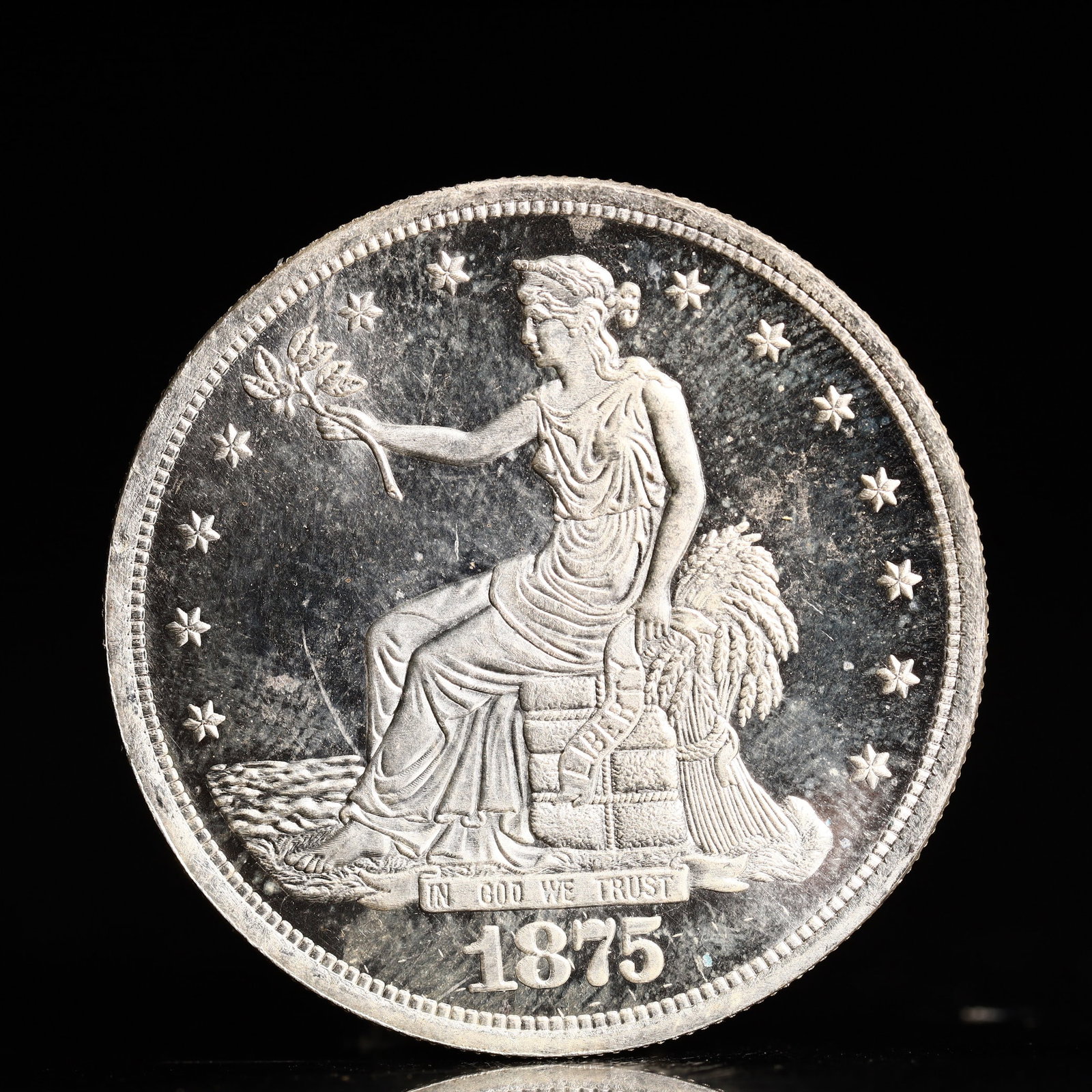 USA Trade Dollar 1875 Coin: American coin. Obverse: Liberty seated on a pedestal facing the sea to the left holding olive branches surrounded by 13 stars. IN GOD WE TRUST / LIBERTY / 1875. Reverse: An eagle holding branches with