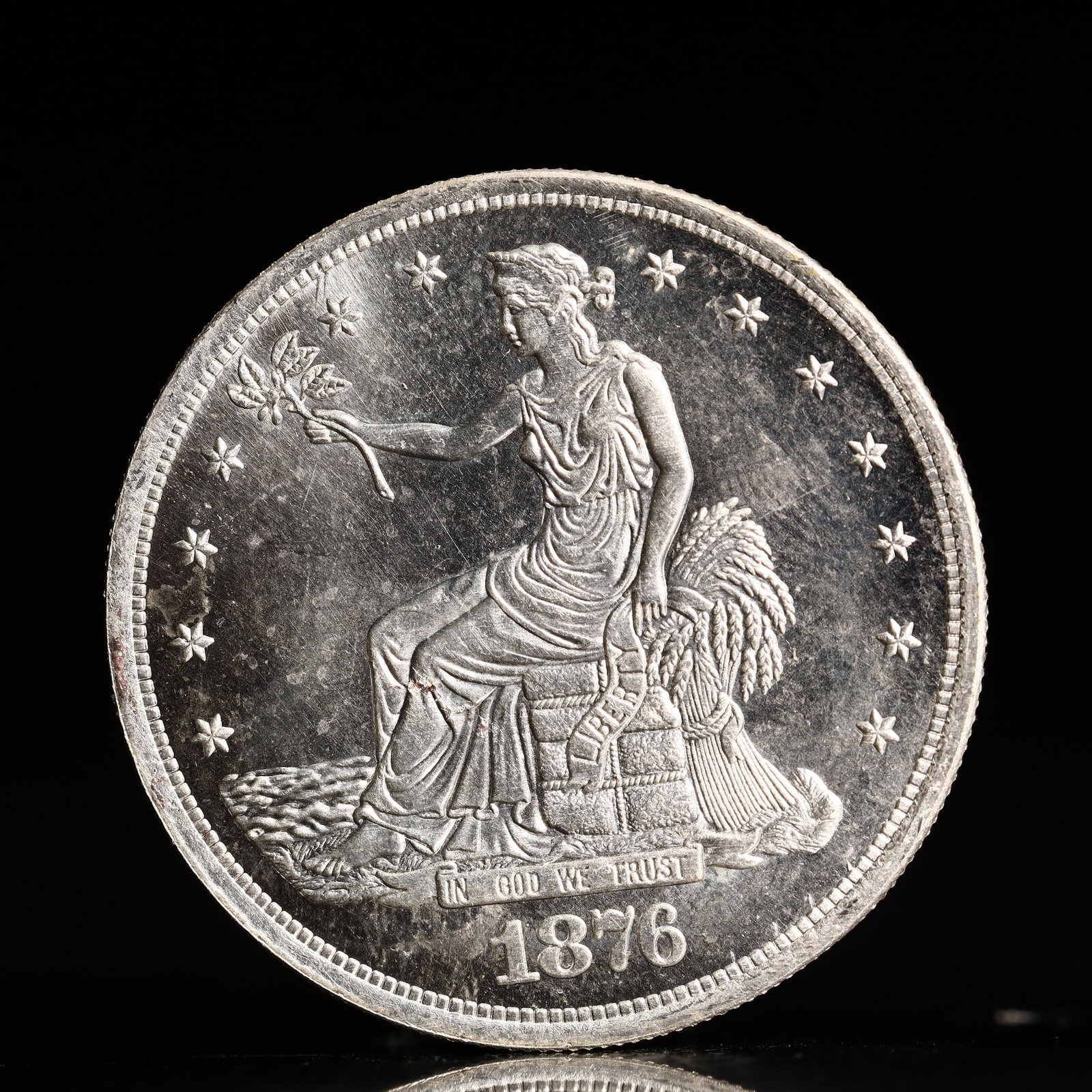 USA Trade Dollar 1876 Coin: American coin. Obverse: Liberty seated on a pedestal facing the sea to the left holding olive branches surrounded by 13 stars. IN GOD WE TRUST / LIBERTY / 1876. Reverse: An eagle holding branches with