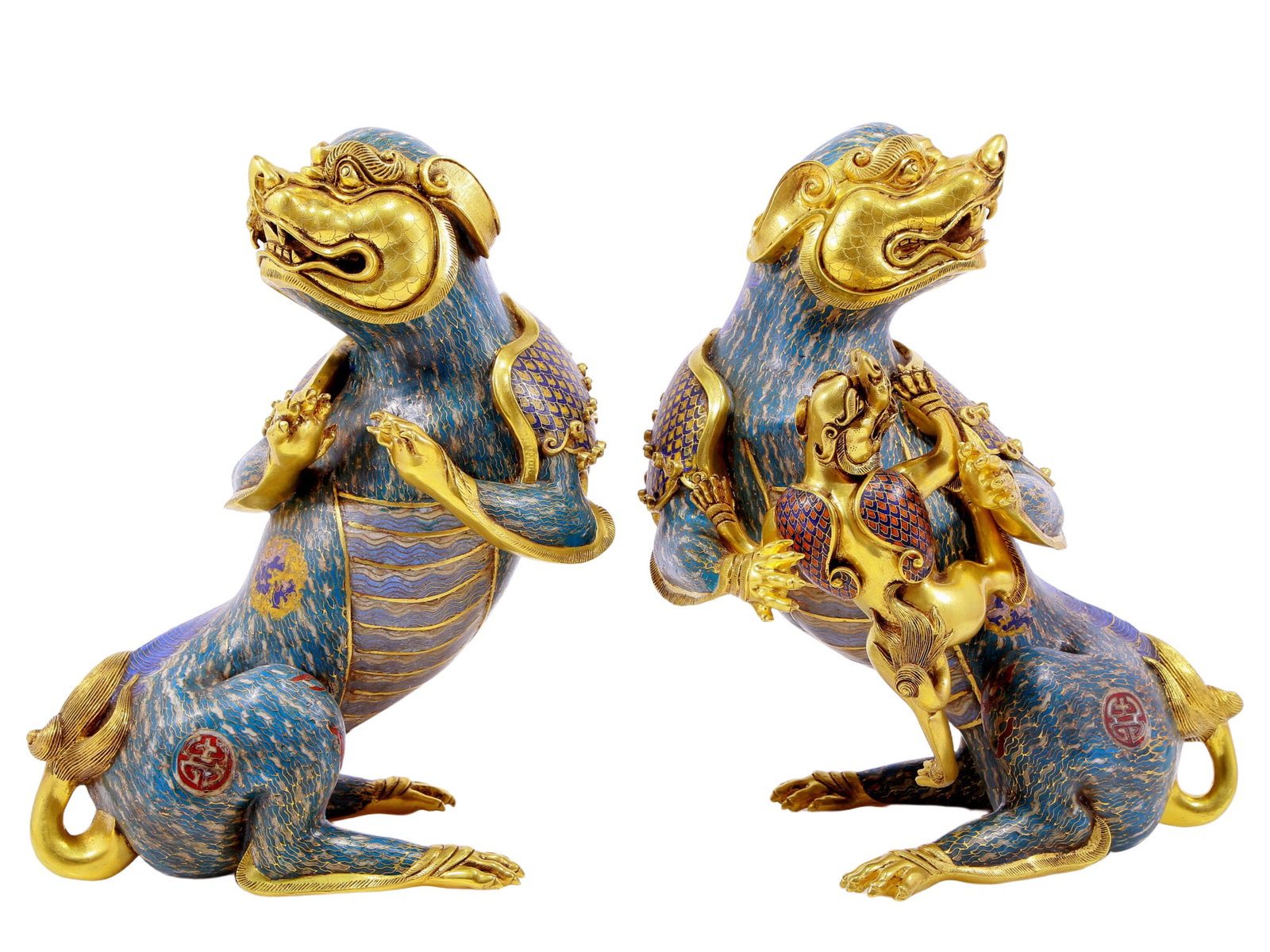 An Exquisite Pair Of Cloisonne Auspicious Beasts: An Exquisite Pair Of Cloisonne Auspicious Beasts. Each's head is of gilt-metal and cast with rounded, bulging eyes, mouth open, revealing fangs; body enameled with polychrome patterns, all reserved on