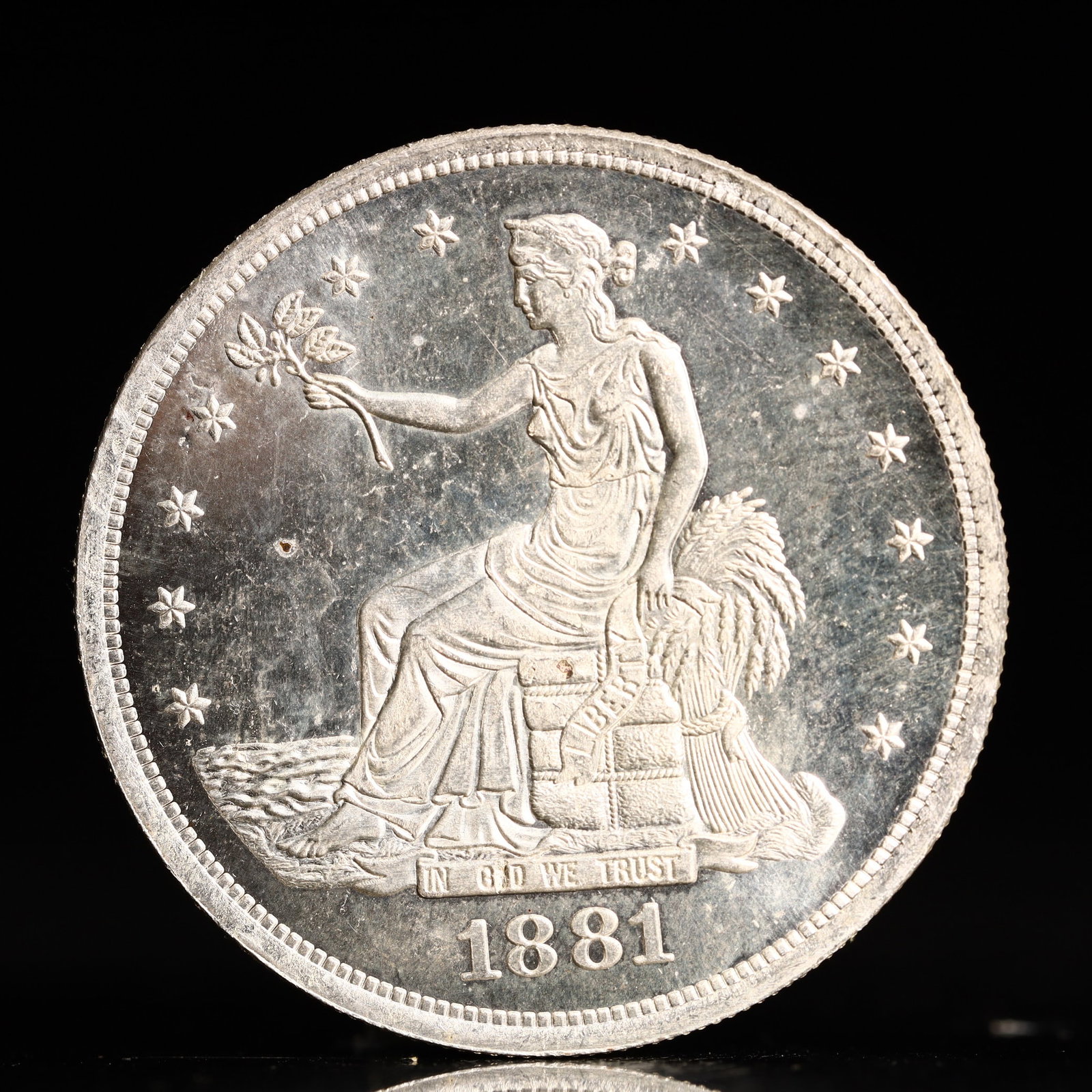 USA Trade Dollar 1881 Coin: American coin. Obverse: Liberty seated on a pedestal facing the sea to the left holding olive branches surrounded by 13 stars. IN GOD WE TRUST / LIBERTY / 1881. Reverse: An eagle holding branches with