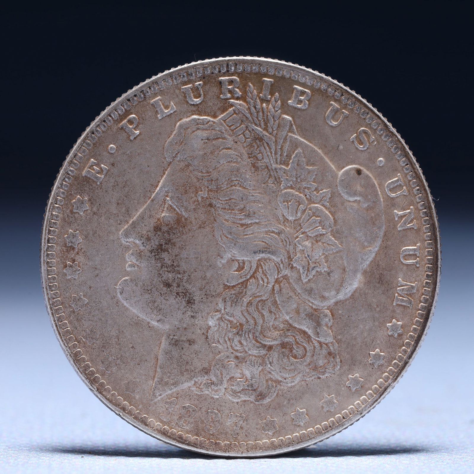 USA Morgan Dollar 1897 Coin: Obv: profile bust with date below and E PLURIBUS UNUM legend and stars around. Rev: eagle with In God we trust above within wreath with UNITED STATES OF AMERICA ONE DOLLAR legend. IN GOD WE TRUST /