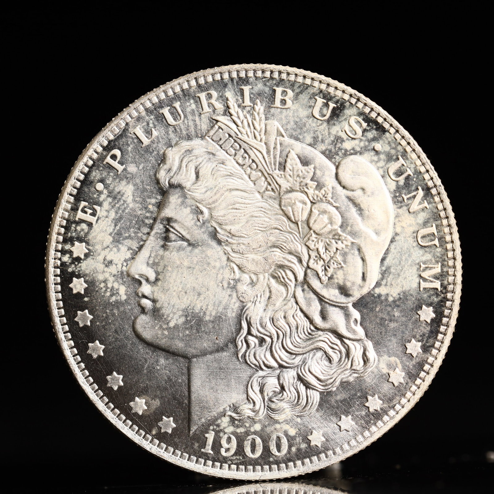 USA Morgan Dollar 1900 Coin: Obv: profile bust with date below and E PLURIBUS UNUM legend and stars around. Rev: eagle with In God we trust above within wreath with UNITED STATES OF AMERICA ONE DOLLAR legend. IN GOD WE TRUST / LI