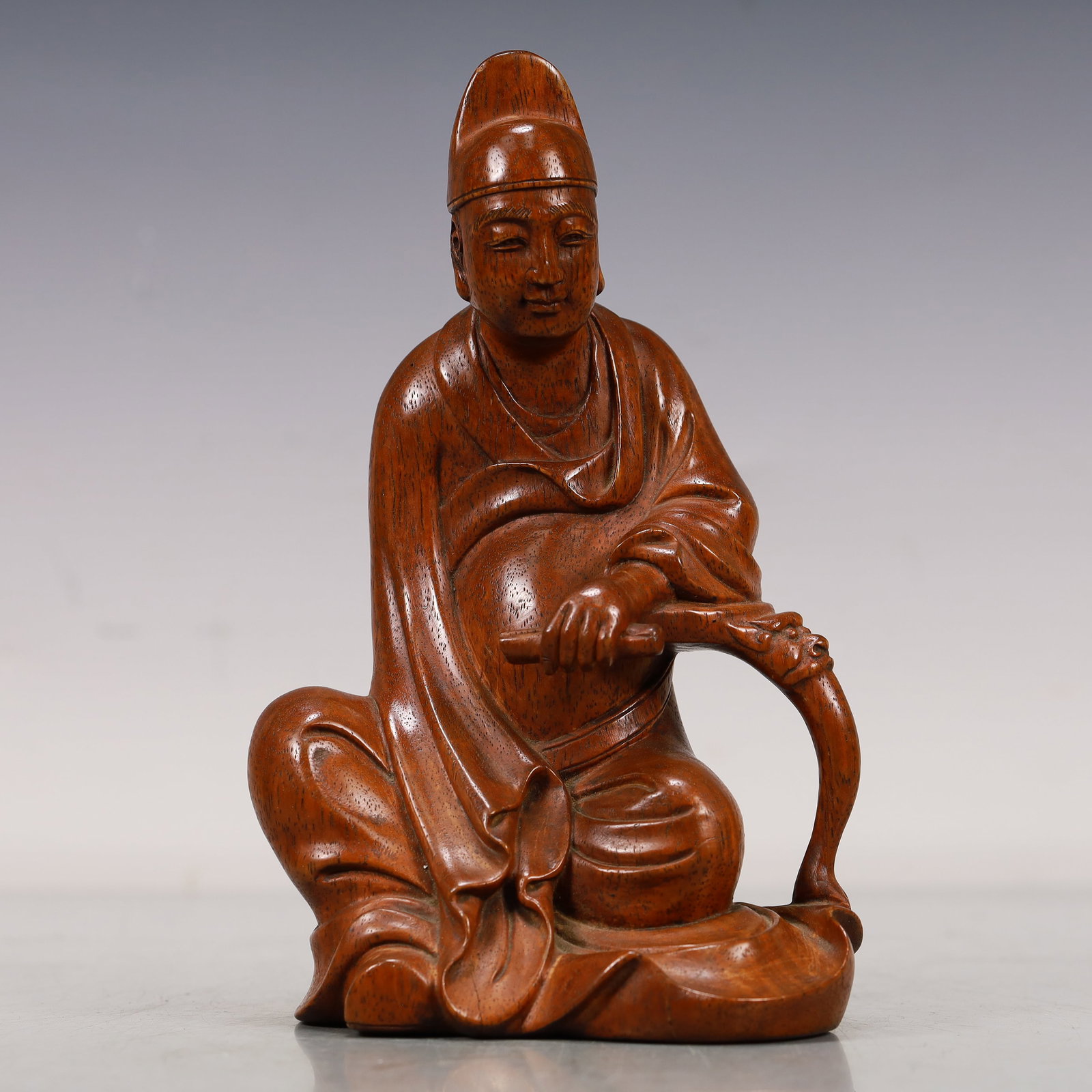 A Huanghuali Wood Figure: A Huanghuali Wood Figure. The figure is seated,body rendered clad in a robe,the voluminous drapery elegantly cascading in folds. Chinese Qing Dynasty. Size:4.3inx3.3inx7.7in 清代