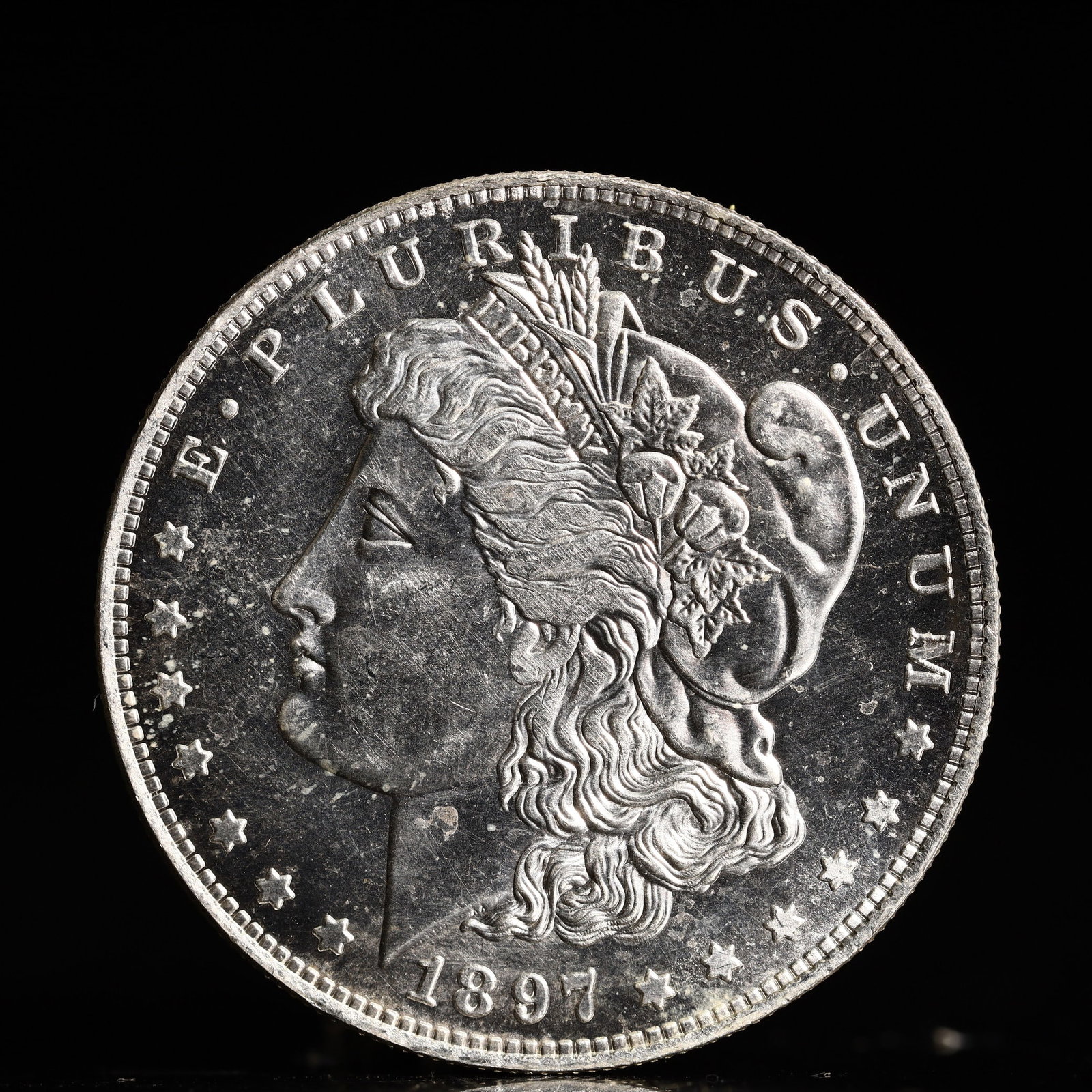 USA Morgan Dollar 1897 Coin: Obv: profile bust with date below and E PLURIBUS UNUM legend and stars around. Rev: eagle with In God we trust above within wreath with UNITED STATES OF AMERICA ONE DOLLAR legend. IN GOD WE TRUST / LI