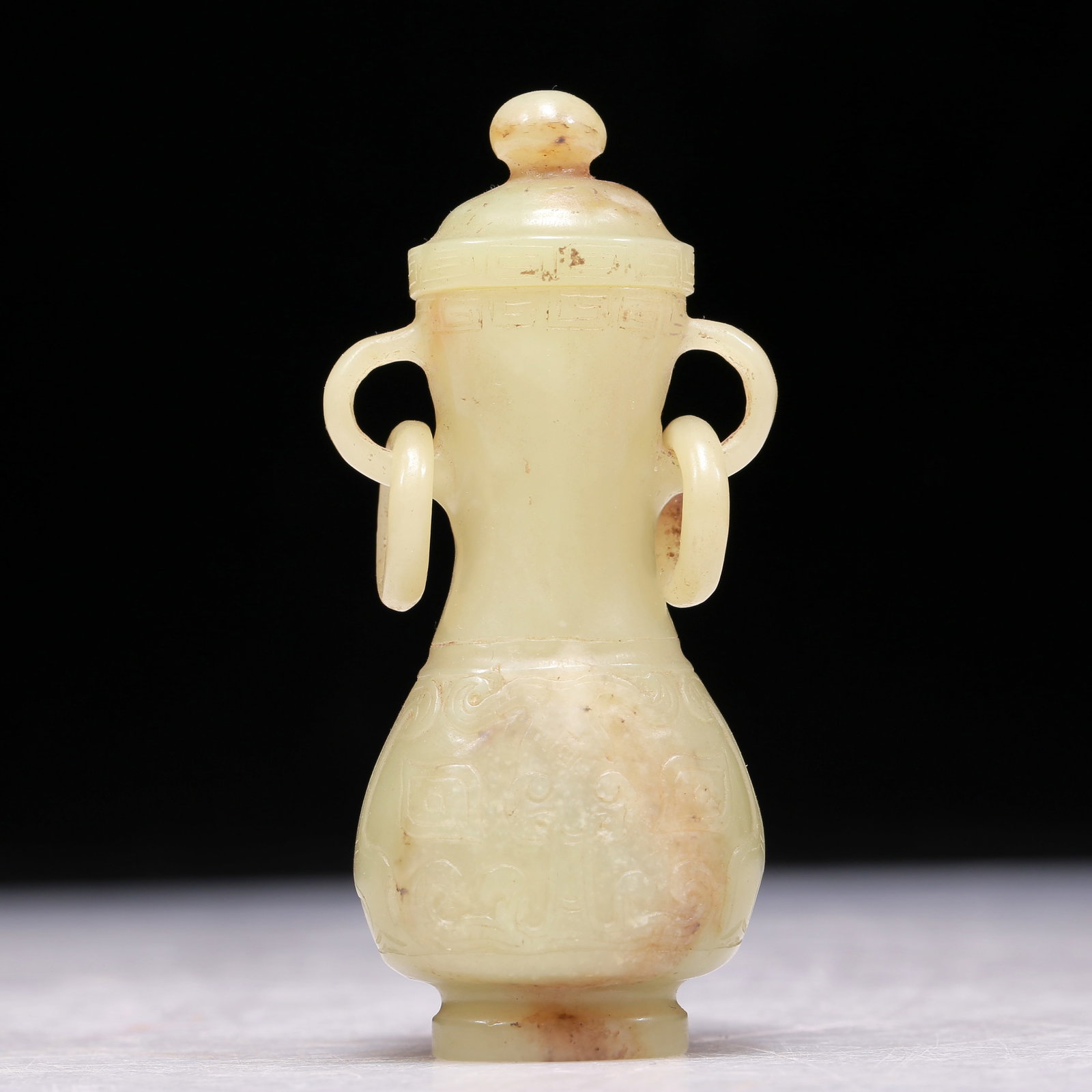 A Precious Miniature Yellow Jade 'Animal Mask' Vase And Cover: A Precious Miniature Yellow Jade 'Animal Mask' Vase And Cover. Supported on a subtly splayed foot, body carved with archaistic motifs, handles with suspending, loose rings. Chinese Qing Dynasty. Size: