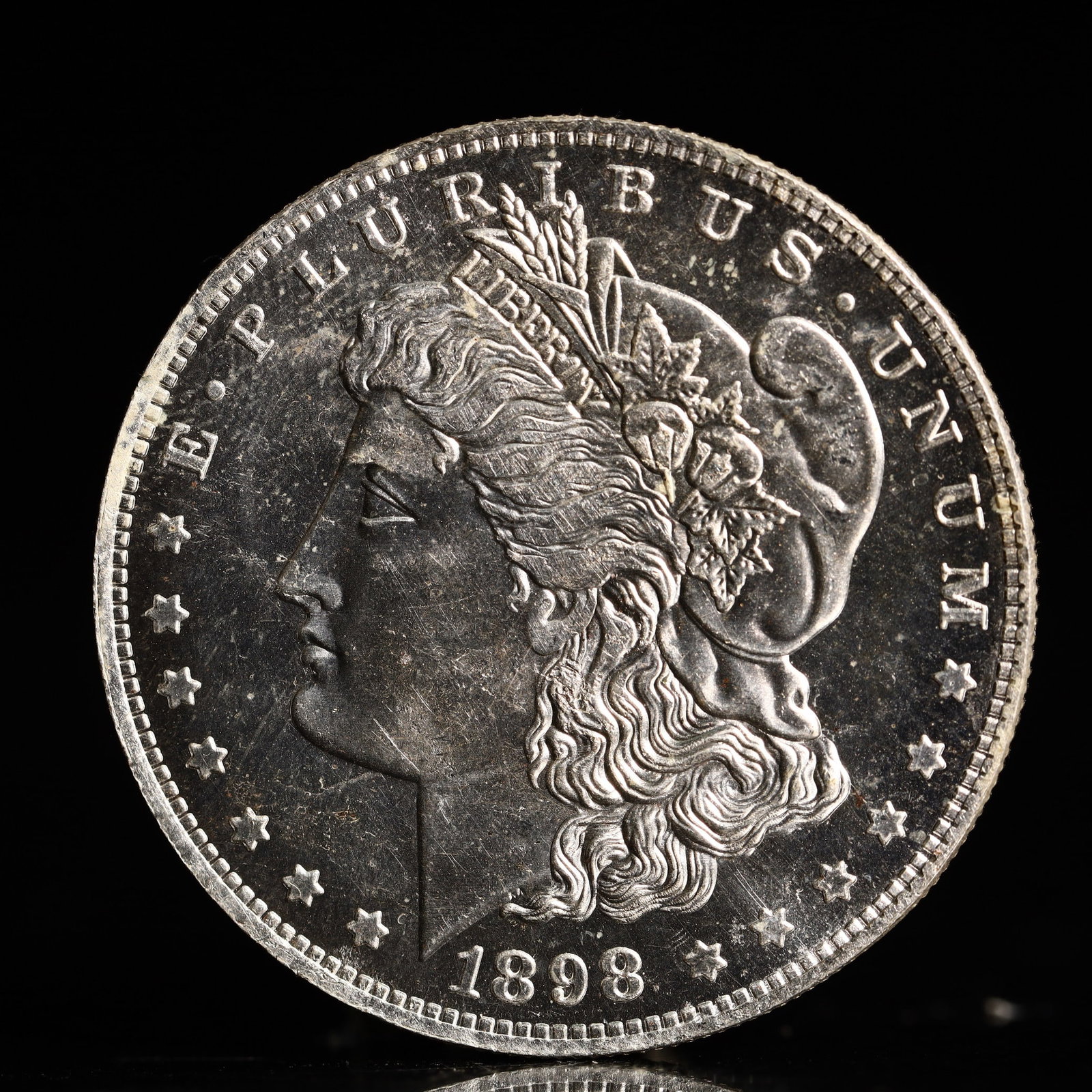 USA Morgan Dollar 1898 Coin: Obv: profile bust with date below and E PLURIBUS UNUM legend and stars around. Rev: eagle with In God we trust above within wreath with UNITED STATES OF AMERICA ONE DOLLAR legend. IN GOD WE TRUST / LI