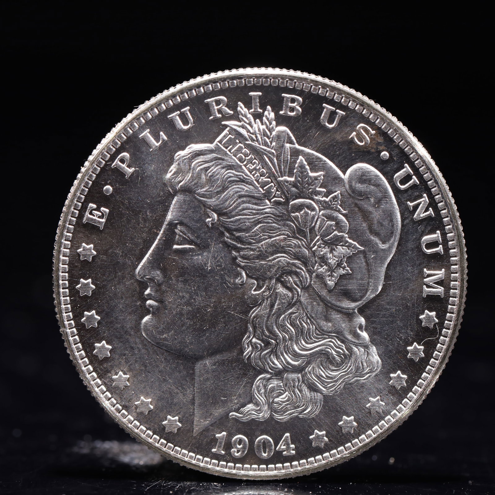 USA Morgan Dollar 1904 Coin: Obv: profile bust with date below and E PLURIBUS UNUM legend and stars around. Rev: eagle with In God we trust above within wreath with UNITED STATES OF AMERICA ONE DOLLAR legend. IN GOD WE TRUST / LI
