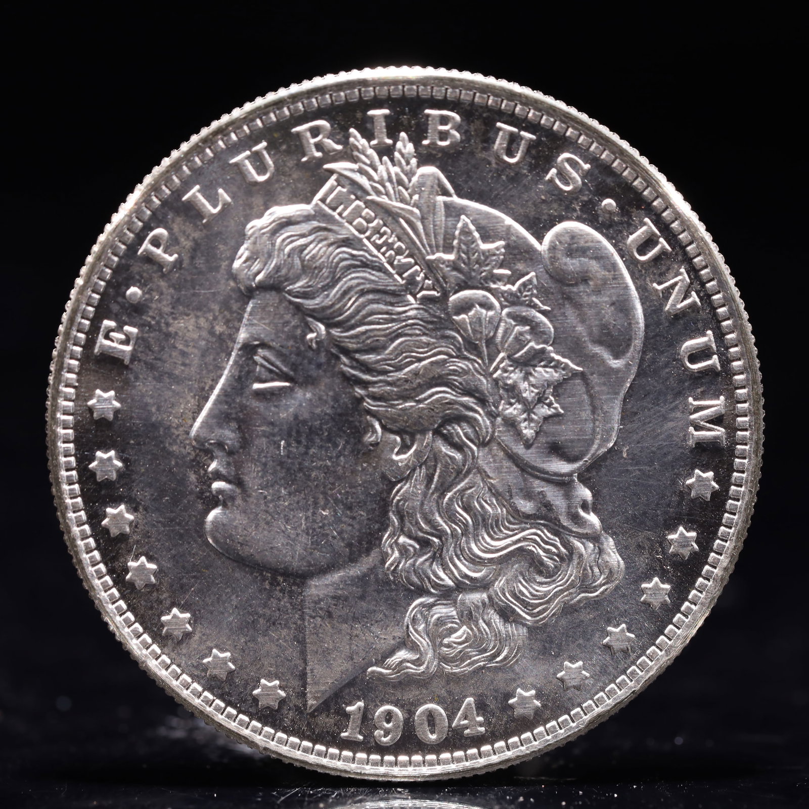 USA Morgan Dollar 1904 Coin: Obv: profile bust with date below and E PLURIBUS UNUM legend and stars around. Rev: eagle with In God we trust above within wreath with UNITED STATES OF AMERICA ONE DOLLAR legend. IN GOD WE TRUST / LI