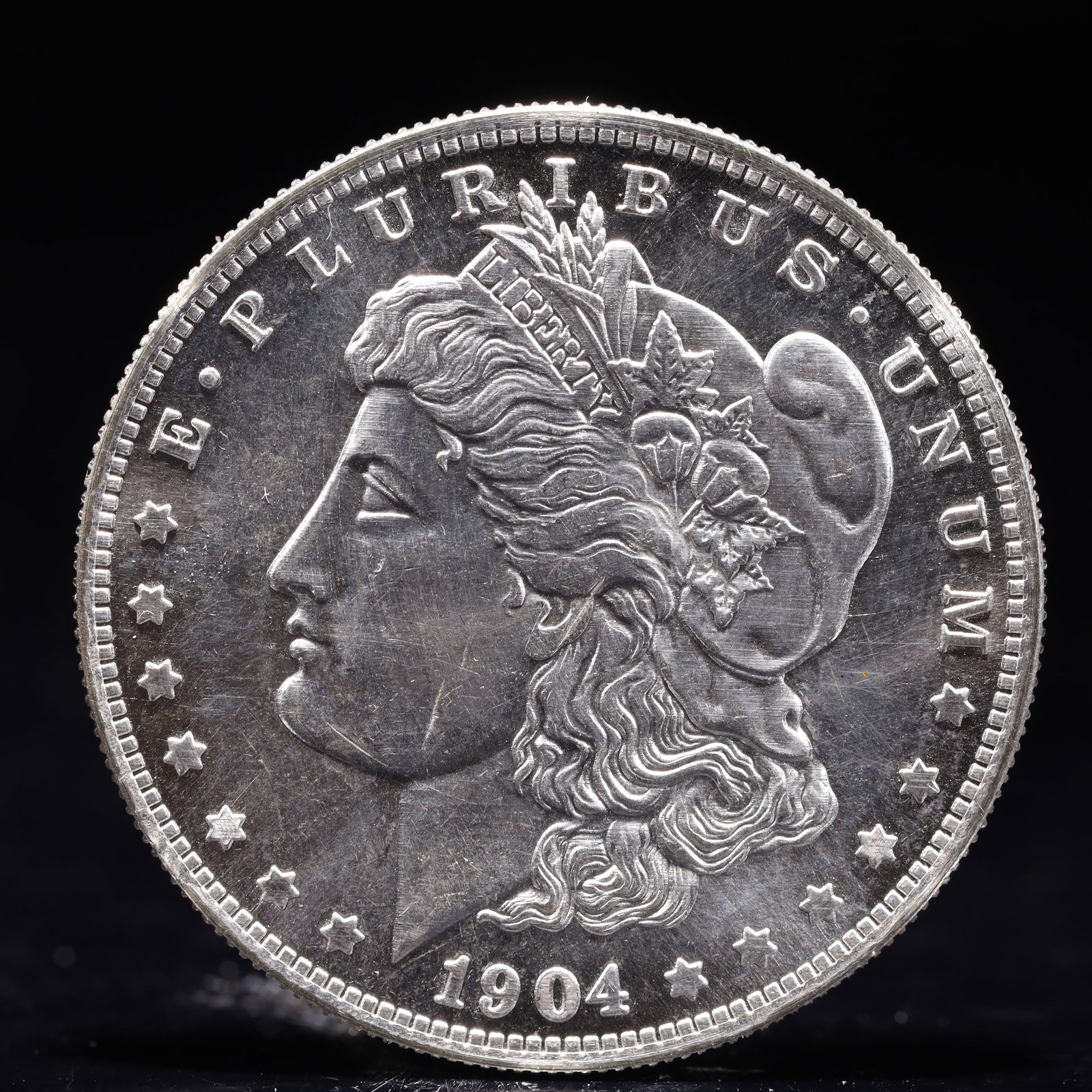USA Morgan Dollar 1904 Coin: Obv: profile bust with date below and E PLURIBUS UNUM legend and stars around. Rev: eagle with In God we trust above within wreath with UNITED STATES OF AMERICA ONE DOLLAR legend. IN GOD WE TRUST / LI