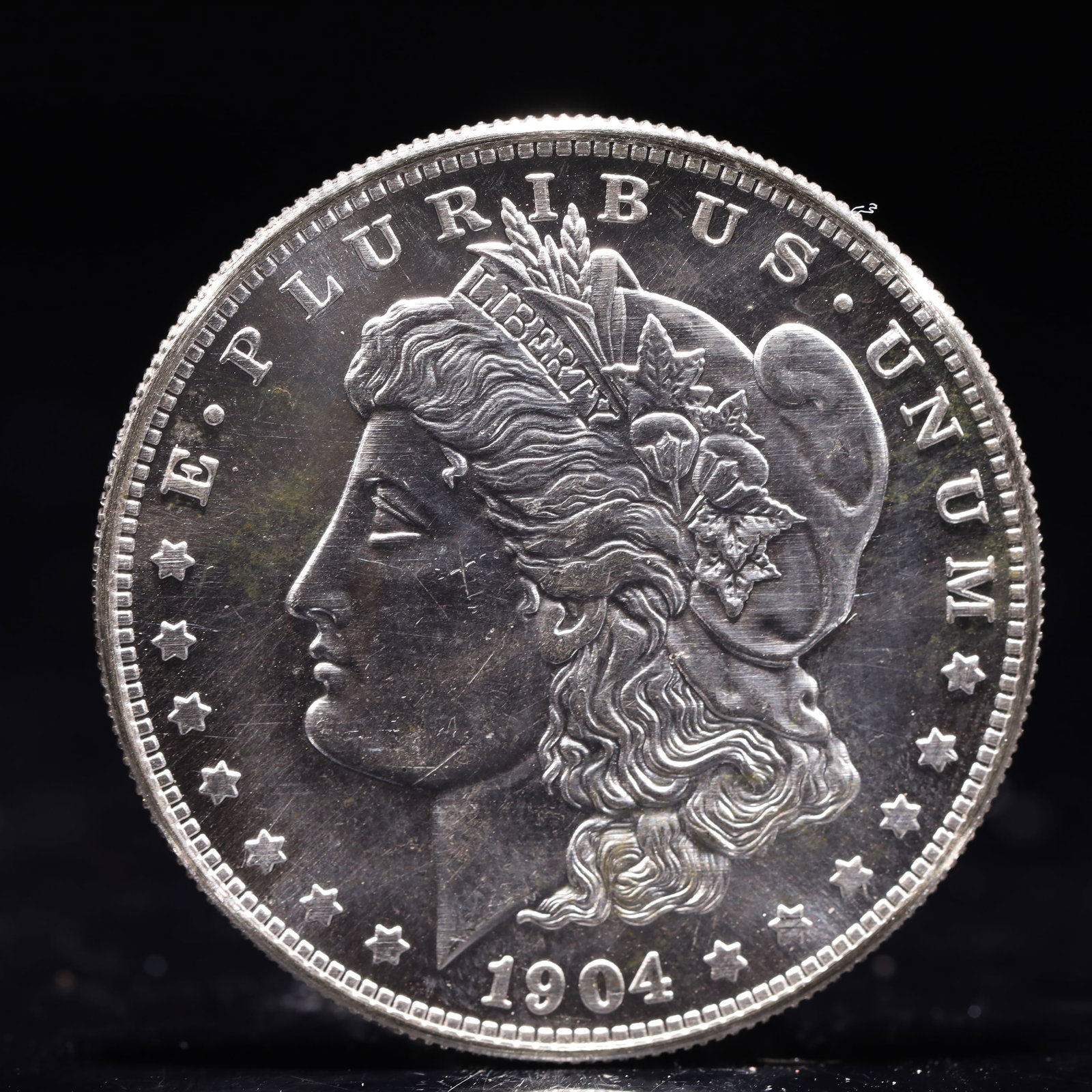 USA Morgan Dollar 1904 Coin: Obv: profile bust with date below and E PLURIBUS UNUM legend and stars around. Rev: eagle with In God we trust above within wreath with UNITED STATES OF AMERICA ONE DOLLAR legend. IN GOD WE TRUST / LI