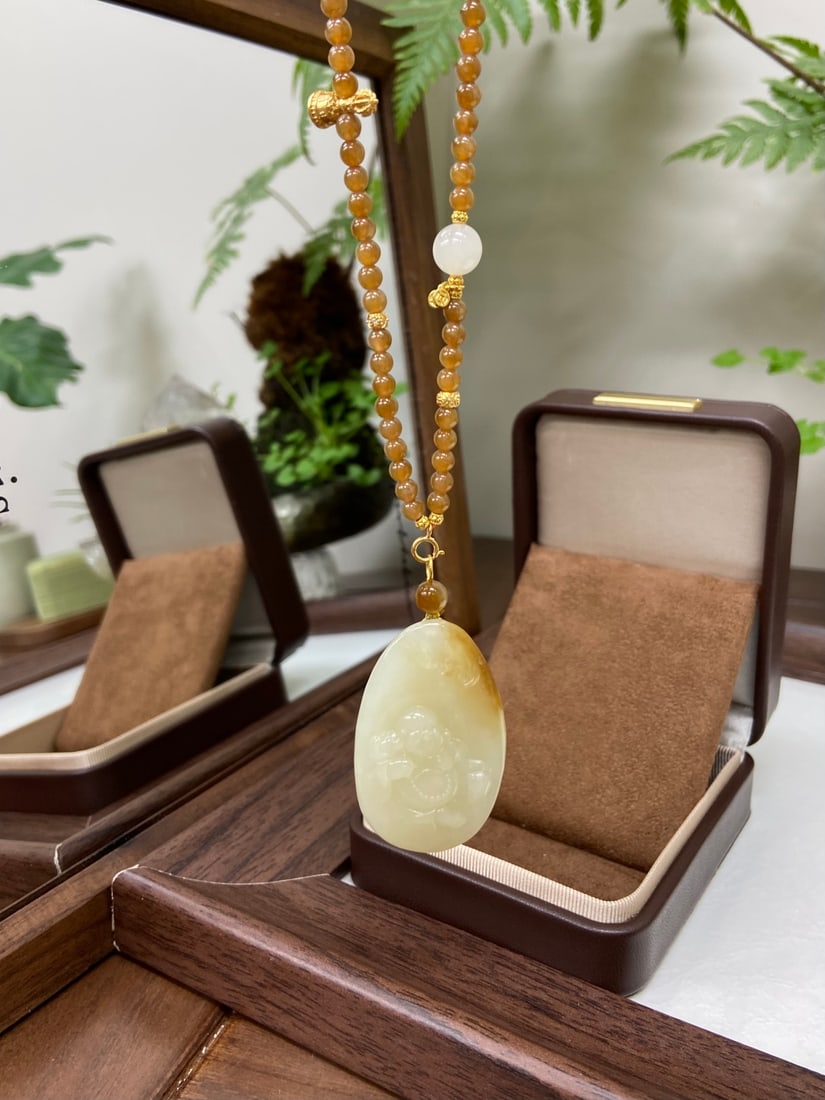 An Exquisite Guan yao Celadon Glazed Painted Gold Double-Ears Vase,with an Imperial Poem by Emperor: A Hetian jade pendant of Qiemo origin, carved as a seated Maitreya Buddha, the sugary-brown and white tones transitioning naturally. The jade is of fine, oily texture with excellent luster. Accompanie