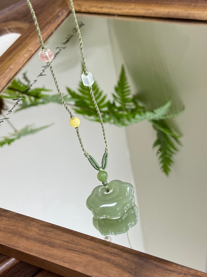 An Exquisite White Jade Beast Ornament: A finely carved Hetian jade pendant of 'gaobing qingshui' (high-ice clear water) quality, carved as an auspicious lock with cloud motifs, symbolizing protection and blessing. The jade is of icy transl
