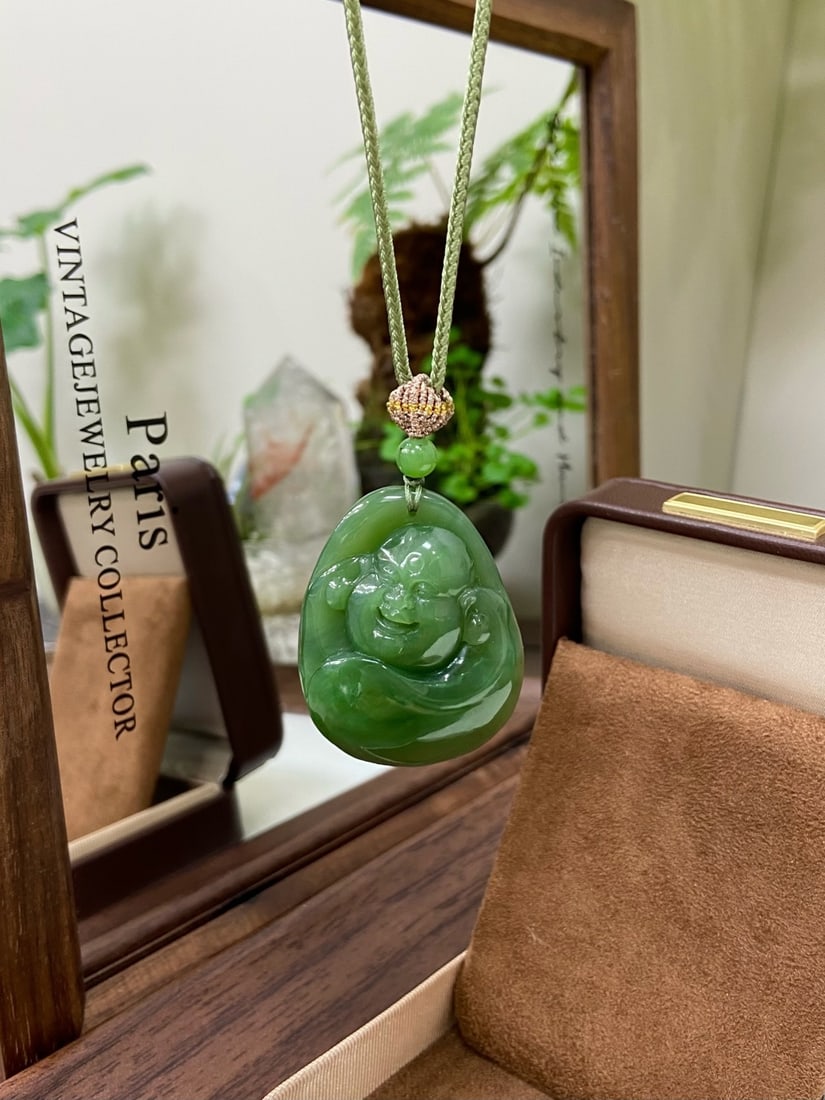 An Exquisite Painted Enamel Flower and Bird Pattern Snuff Bottle: A finely carved Hetian jade pendant of spinach-green tone, carved as a seated Maitreya Buddha. The jade is of rich, vibrant color with a cat's-eye effect when turned in the light. The reverse is carve