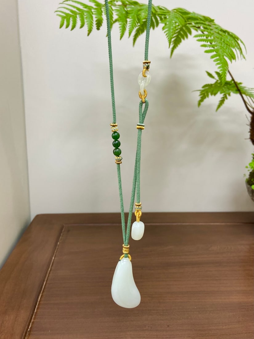 A Solemn Gilt Bronze Statue of Manjusri: A finely carved Hetian jade pendant of 'yangzhi' (mutton-fat) white quality, carved with a motif symbolizing the rising wind and water, a metaphor for prosperity and success. The jade is of