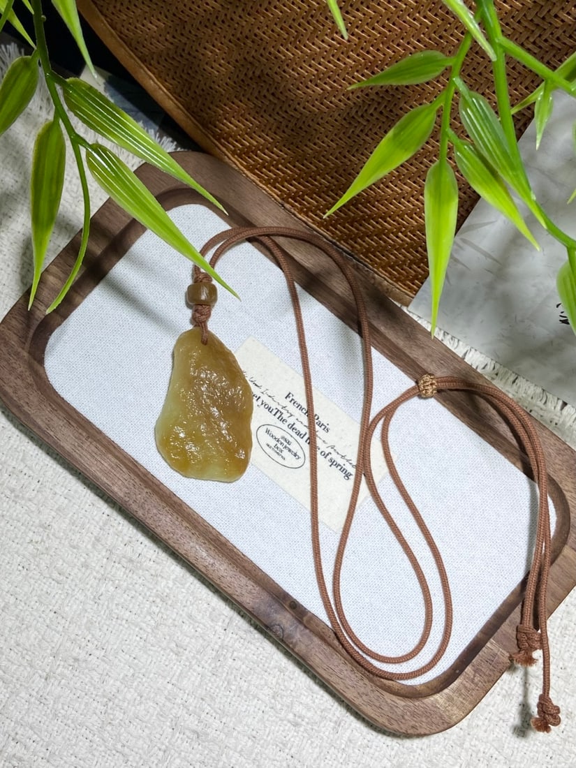 An Archaic Hongshan Culture Yellow Jade Figure Ornament: A natural Hetian jade pendant of Qiemo origin, left in its rough, unpolished state, yet already exhibiting remarkable oiliness and warmth. The pendant measures 45.6mm by 29.3mm by 11.2mm. 和