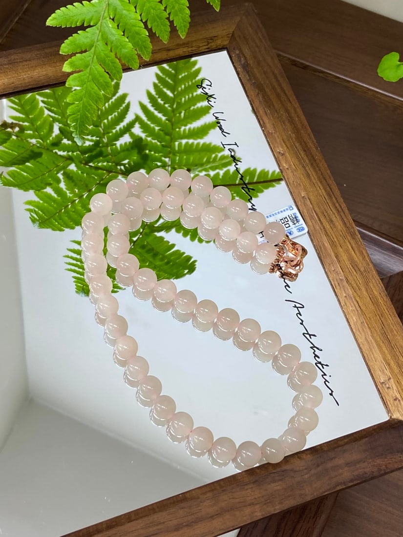 An Exquisite White Jade Dragon and Phoenix Pattern Pot: A finely carved Hetian jade necklace of 'noubo lotus root' (glutinous-icy oufen) quality, composed of round beads of 10mm diameter. The jade is of fine, even quality with a glossy, translucent finish.