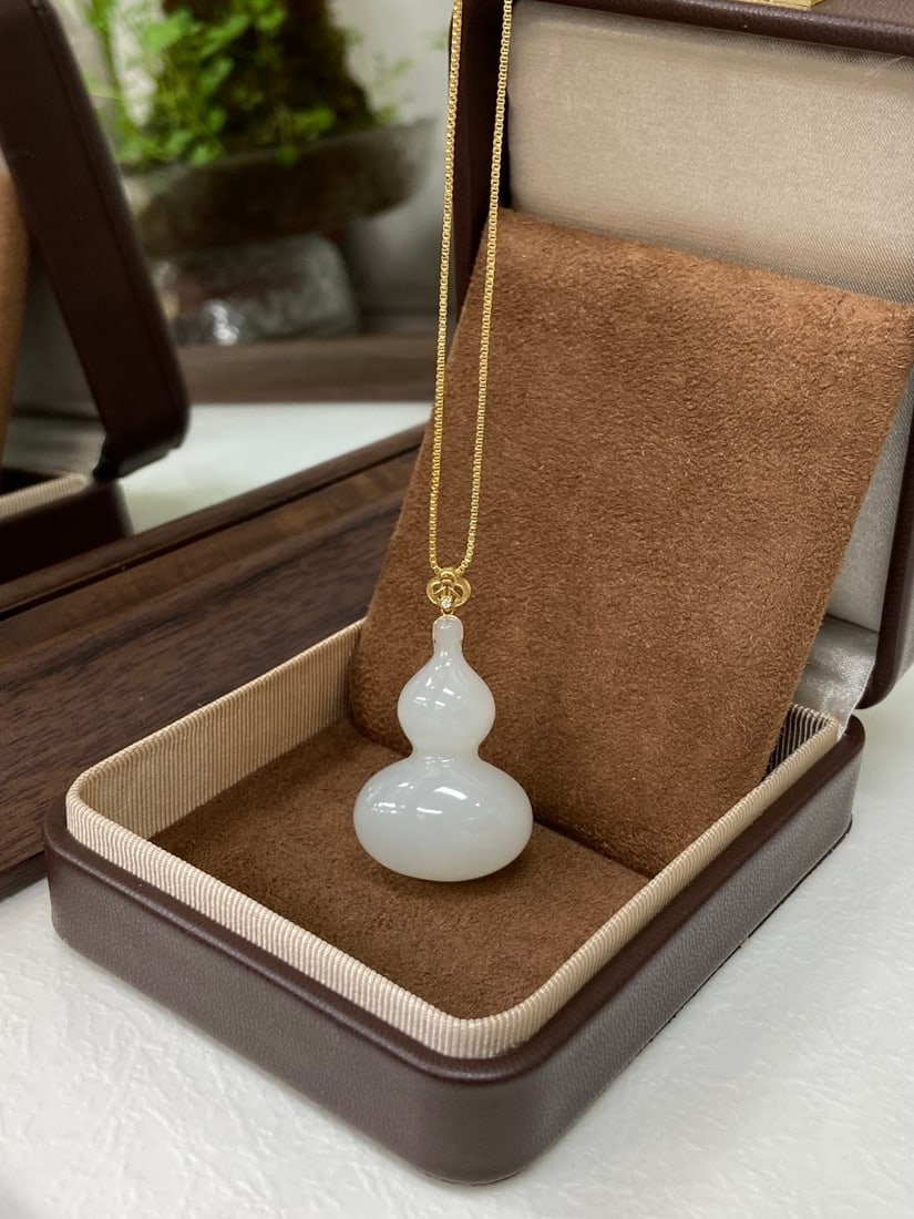 A Chinese Vertical Scroll Ink Painting of Character and Story on Silk: A finely carved Hetian jade pendant, set in 18K gold, carved as a gourd, a symbol of blessing and prosperity. The pendant measures 41mm by 23.7mm by 11.7mm. 和田玉18K金镶